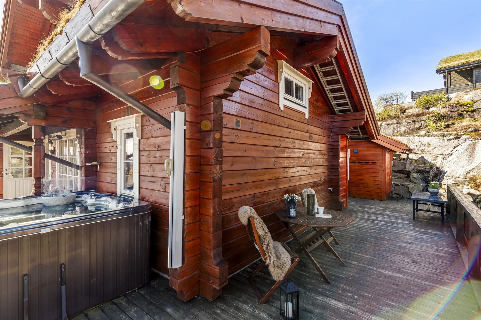Terrassen er belagt med terrassebord og har rekkverk med stående spiler og glassfelter. Galleribilde