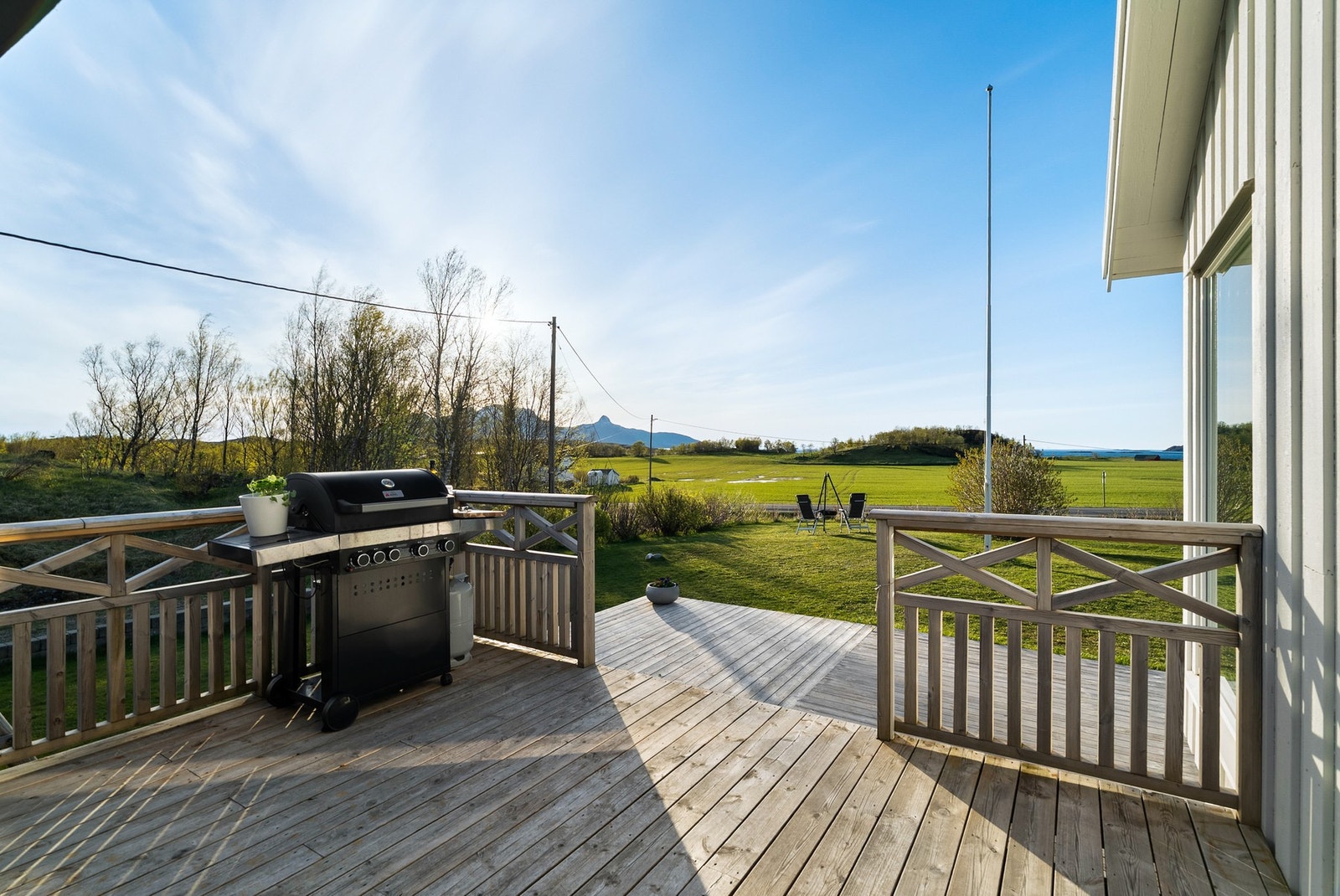 Fra balkongen har man åpen utsikt over de landlige omgivelsene, med trapp ned til terrasse og hage Galleribilde