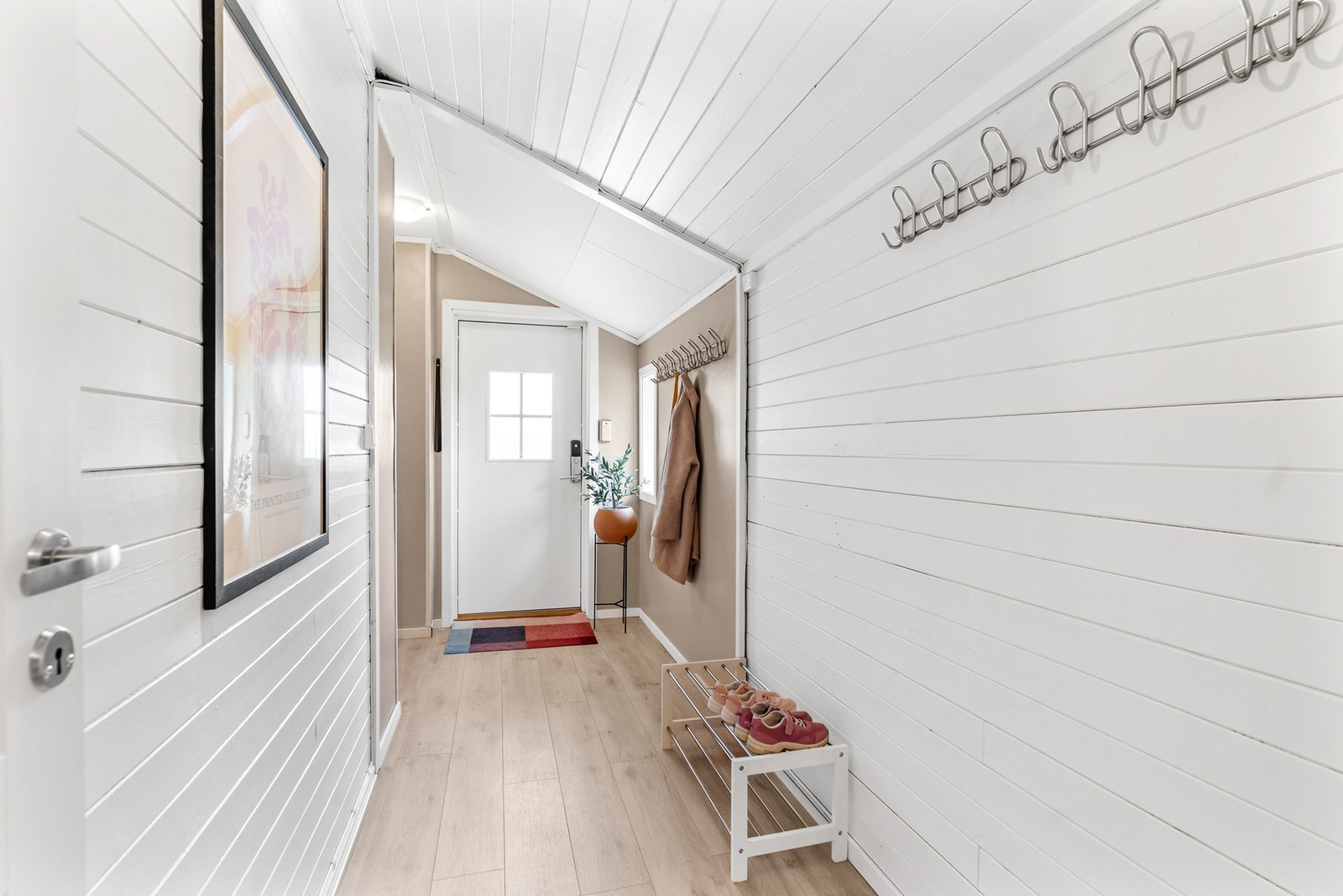 Entréen har malte panelvegger og laminat på gulvet. Galleribilde