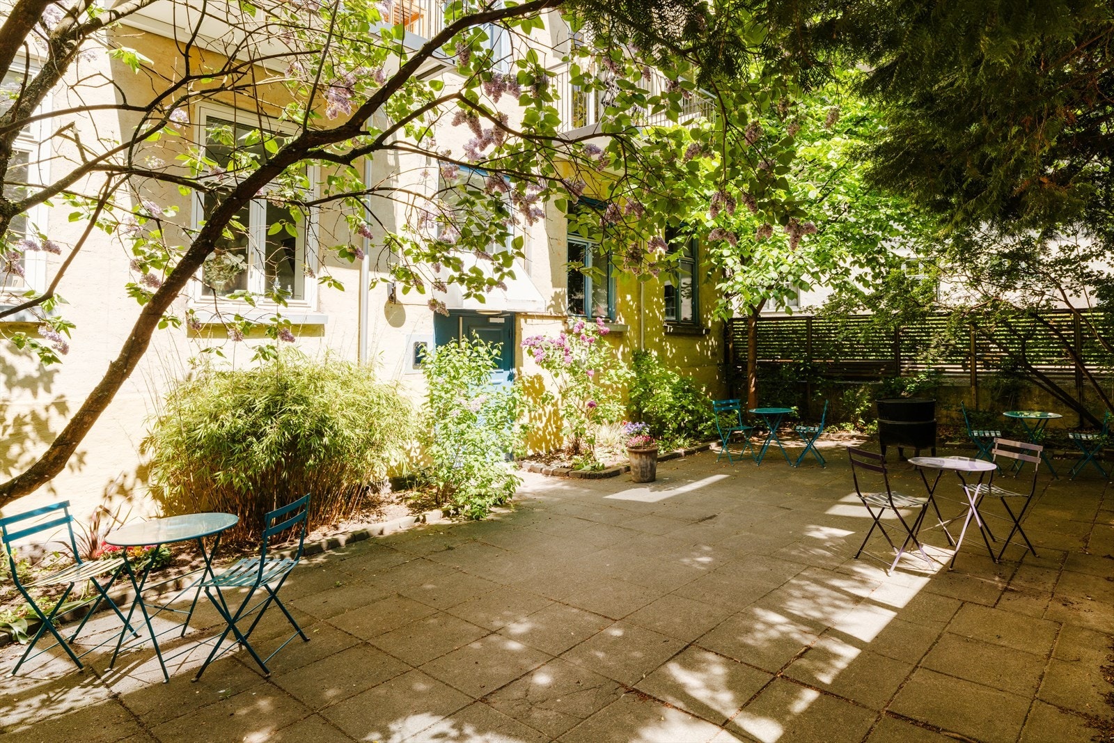 En koselig og lukket bakgård med flere sittegrupper og grill. Galleribilde