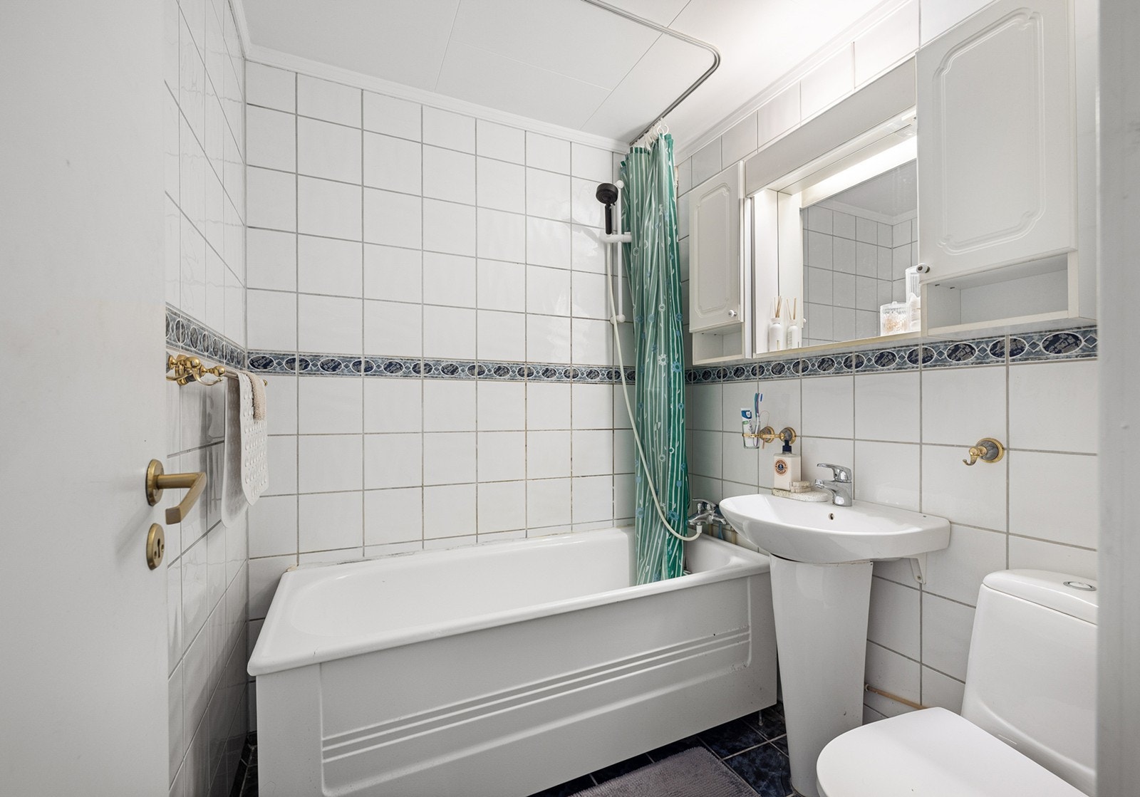 Badet har flislagte gulv og vegger. Rommet er innredet med badekar med dusjløsning. Dette er et baderom med eldre standard, og det må påregnes oppgraderinger over tid for å møte dagens krav og forventninger til moderne våtrom. Galleribilde