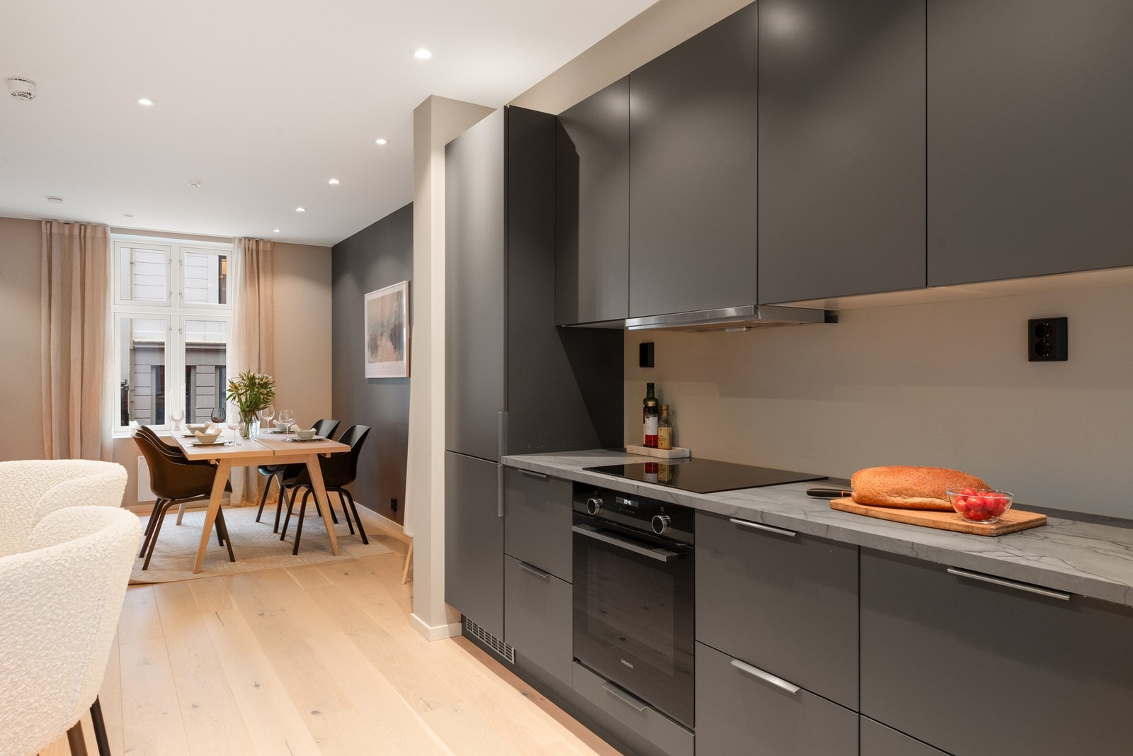 Innredningen har mørke fronter som gir et elegant uttrykk, kombinert med lys benkeplate og integrerte hvitevarer. Galleribilde