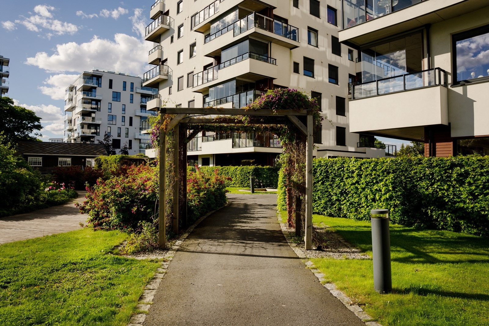 Velstelt uteområde med gangstier, pergola og flotte beplantninger - et hyggelig og grønt bomiljø. Galleribilde