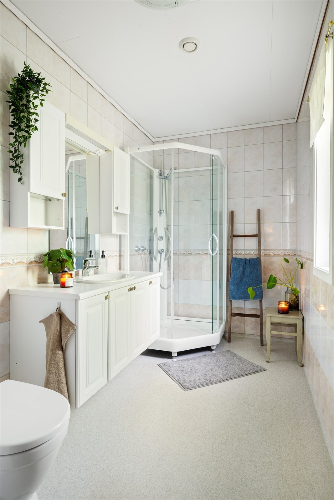 Badet har vinylbelegg på gulv med varme, flislagte vegger og en himling med tak-ess. Galleribilde