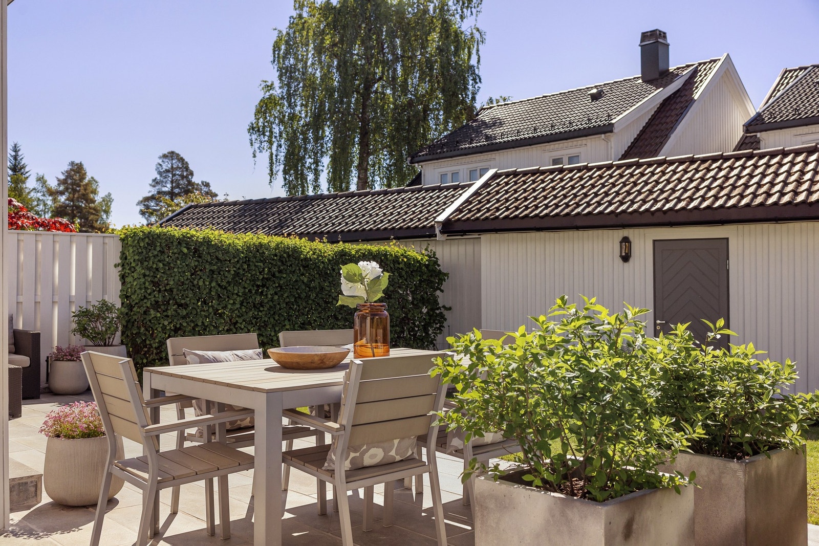 Terrassen har dekke av skifer med enkelte trinn i skifer og betong ned til hagen, og fremstår som et innbydende uteareal. Galleribilde