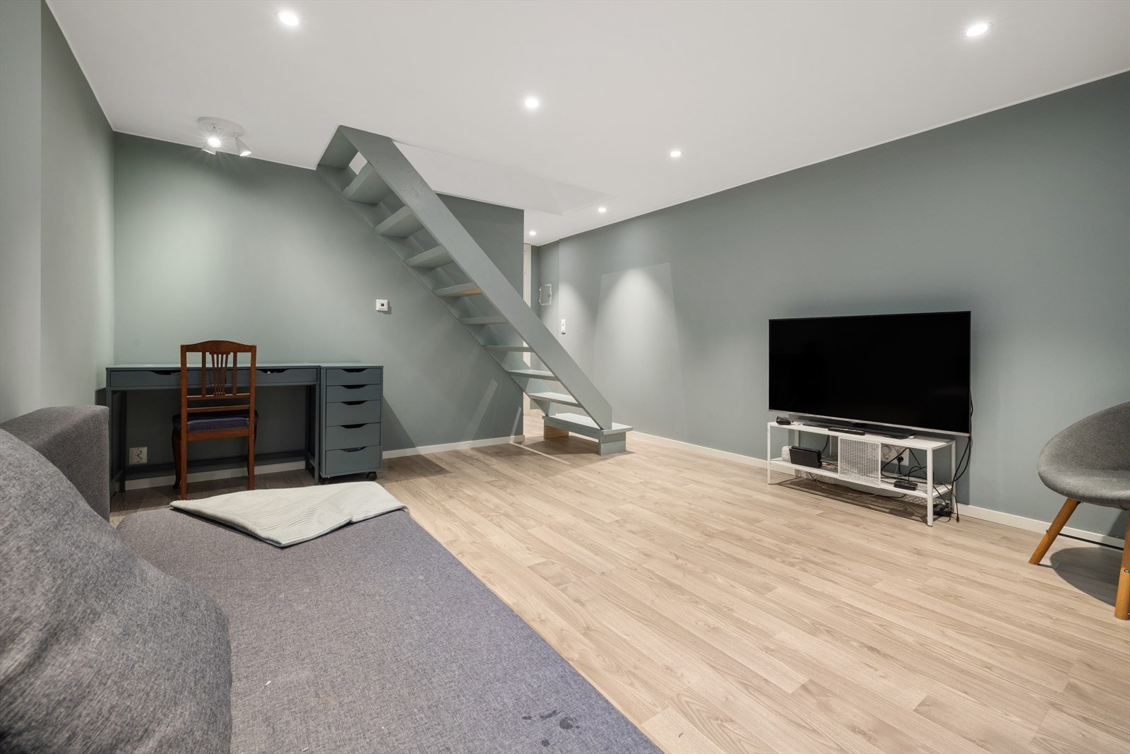 Totalrenovert kjellerstue med ny elektrisitet fra 2021. Dempet grønngrå veggfarge, laminatgulv og downlights i taket. God plass til TV-krok, hjemmekontor eller familierom. Galleribilde