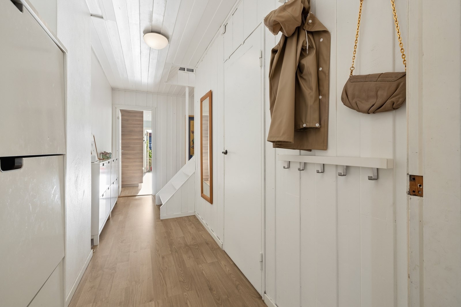 Hvitmalt korridor med trepanel i taket gir et lunt og innbydende preg. Fra entréen er det naturlig adkomst til hovedsoverom, kjøkken og trapp til 2. etasje. Galleribilde