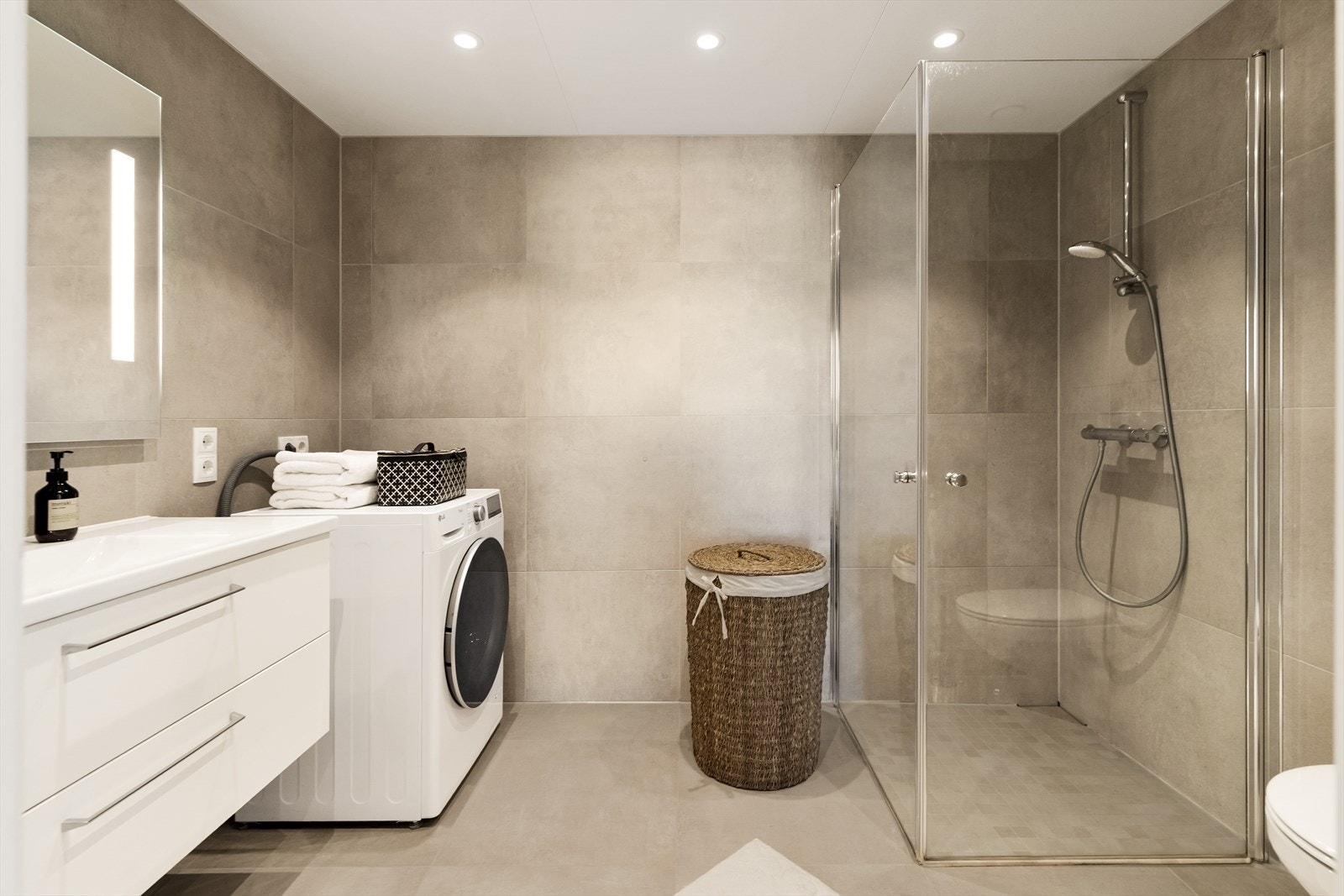 Badet er meget innbydende og delikat med lekre beigetonede fliser på gulv og vegger. Galleribilde