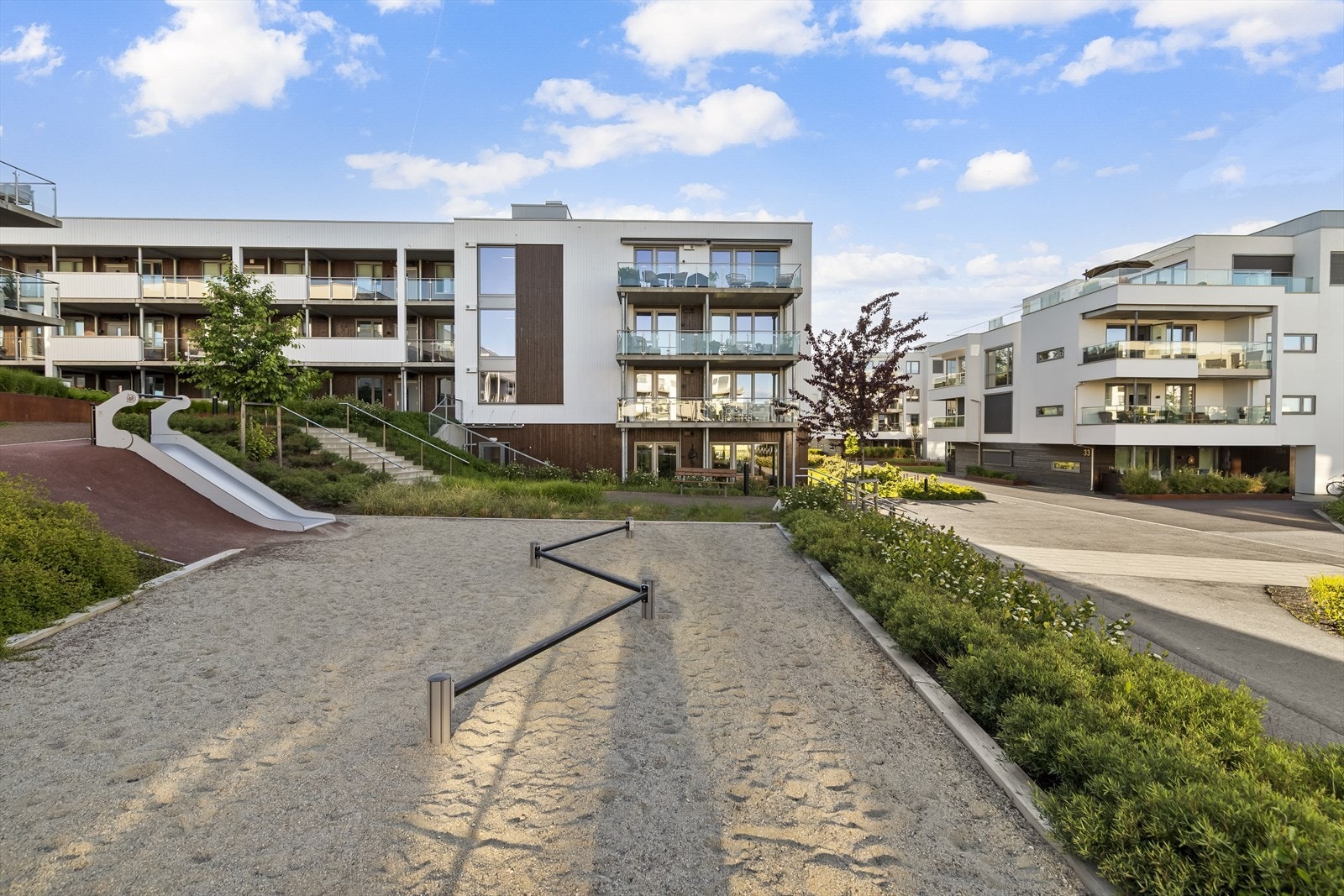 Tomten har store plenareal, diverse beplantning, lekeplass og sittebenker. Galleribilde