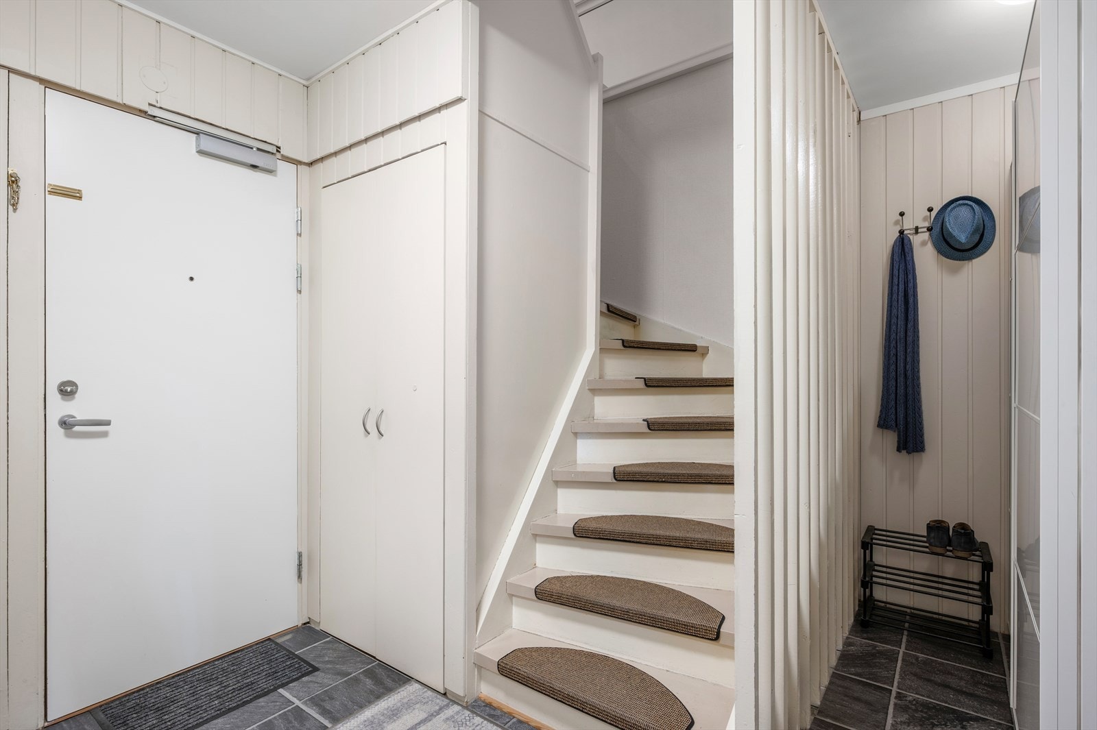 Gang med slikesterkt gulv, klesnisje med garderobeskap og oppbevaringsplass under trapp Galleribilde