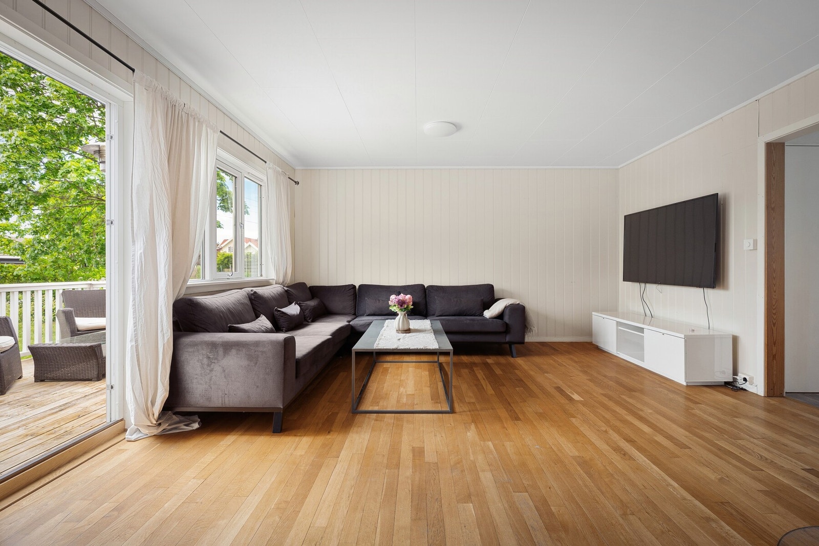 Lys stue med store vindusflater som slipper inn rikelig med naturlig lys og skaper en luftig atmosfære. Rommet har plass til både sofagruppe og tv løsning. Galleribilde
