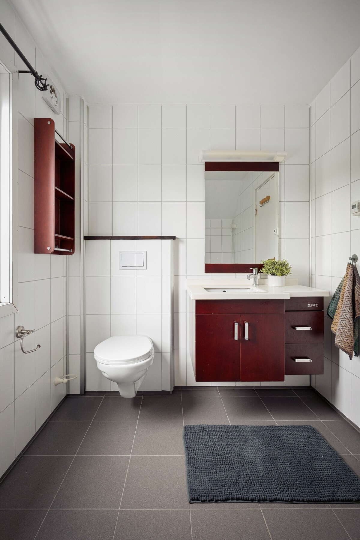 Bad med flislagte overflater og gulvvarme. Badet har mørk baderomsinnredning som skaper en fin kontrast. Galleribilde