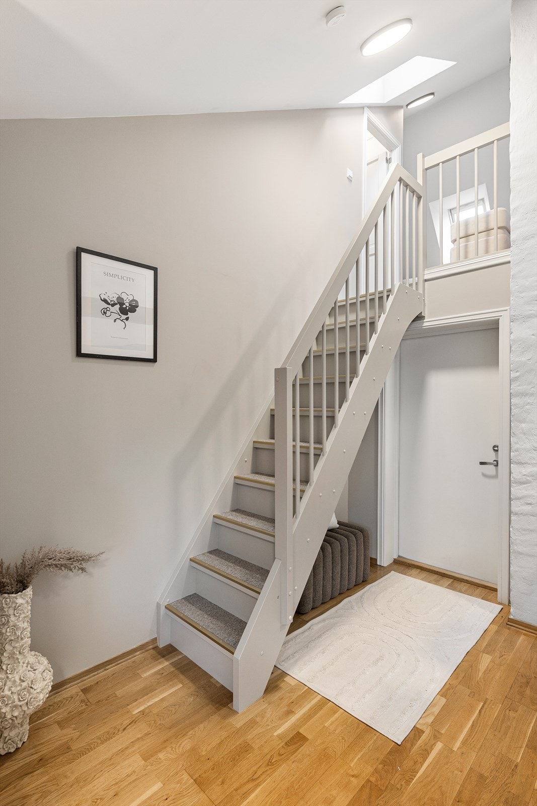 Den interne trappen leder opp til loftsplanet, hvor skrå himlinger, synlige konstruksjonselementer og takvinduer skaper en lun og skjermet atmosfære. Galleribilde