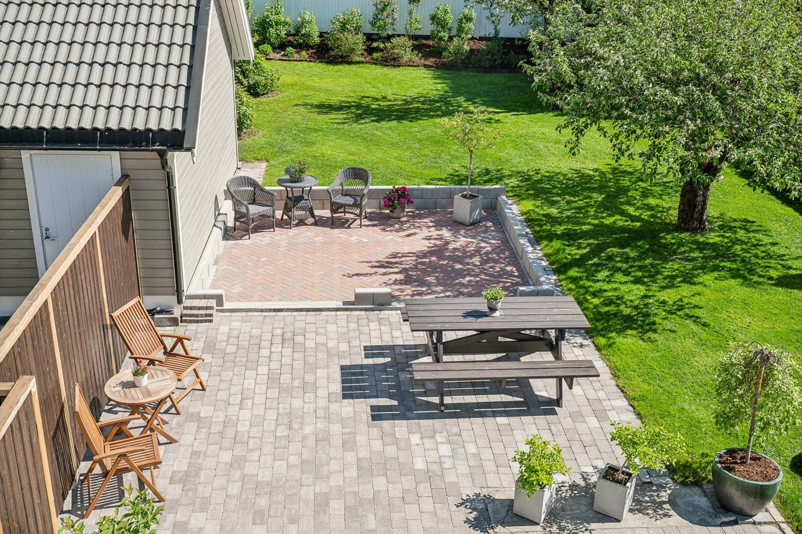 Utsikt fra balkong med solrik terrasse og grønt, velstelt fellesområde med gode sitteplasser. Galleribilde