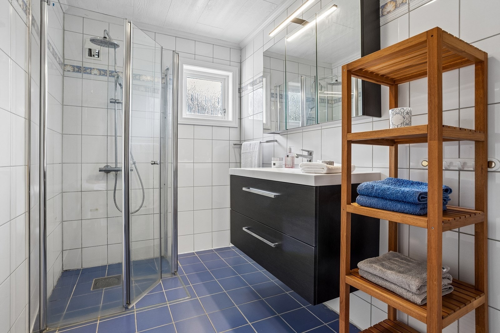 Badet i underetasjen har keramiske fliser, varme i gulvet og dusjhjørne med foldedører i glass. Galleribilde
