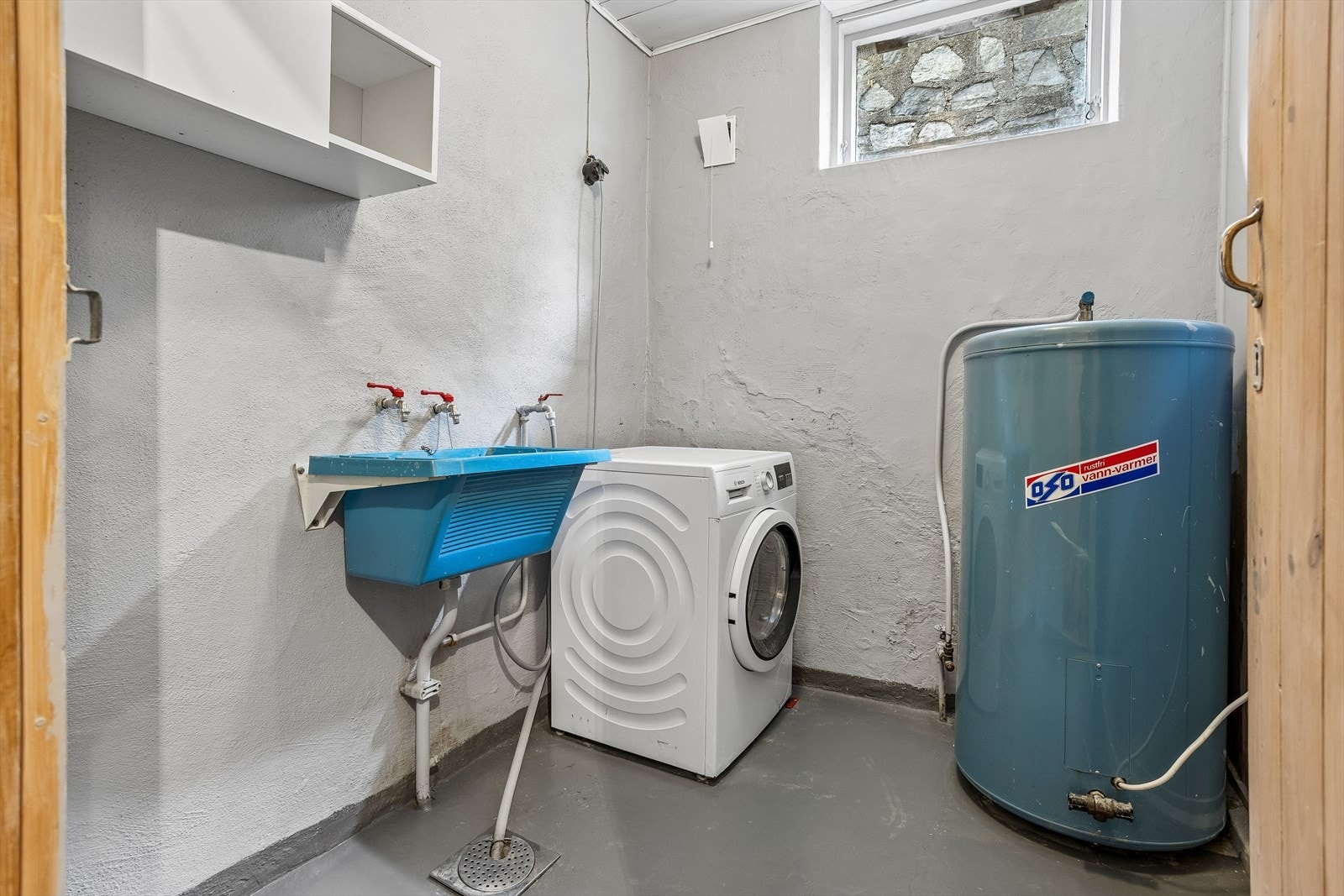 Praktisk vaskerom med malt betonggulv, opplegg for vaskemaskin og egen skyllekum. Galleribilde