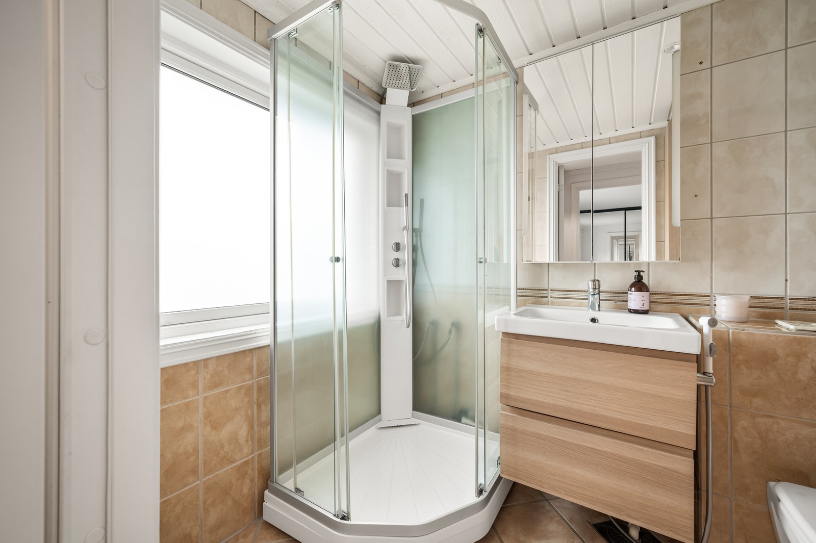 Badet i 2. etasje fremstår lyst og innbydende med varme toner og praktiske løsninger. Galleribilde