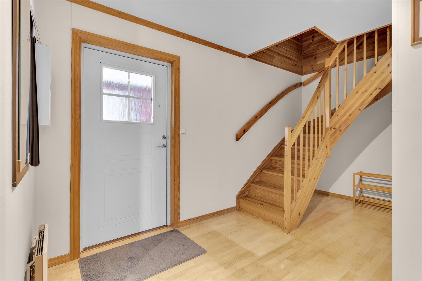 Lys entré med plass til yttertøy. Den lukkede trappen i lakkert tre leder opp til loftsetasjen. Galleribilde