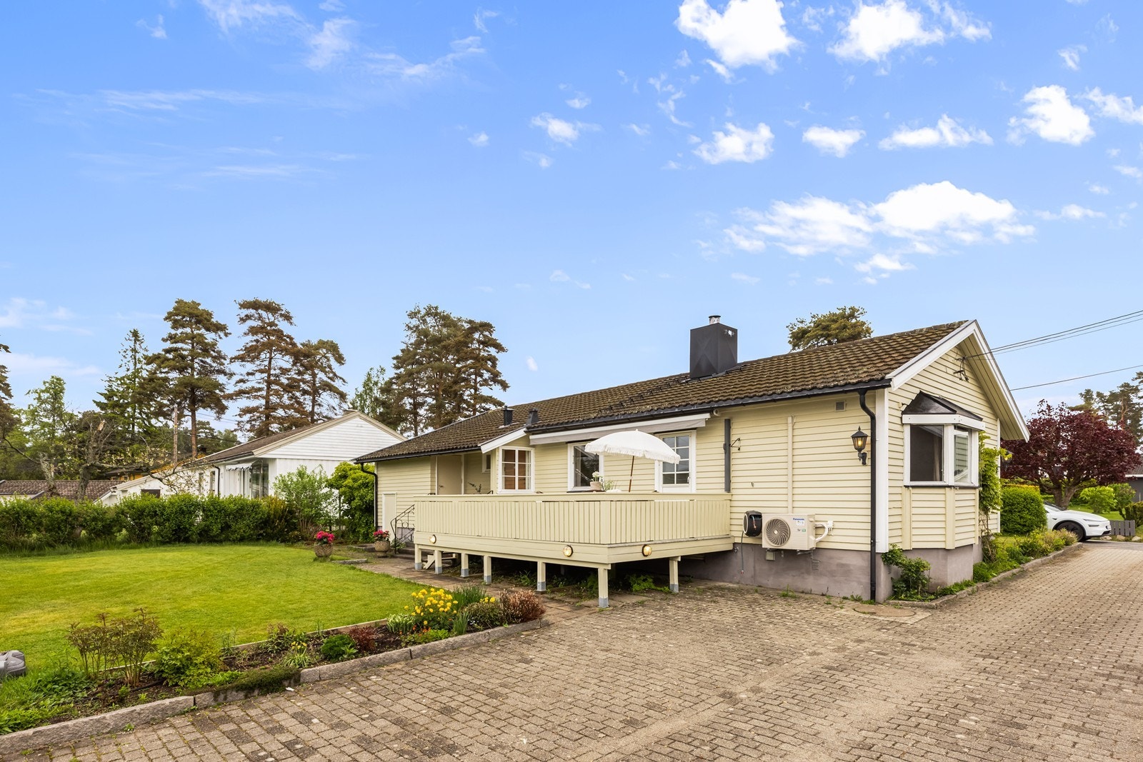 Fra hagen er det god oversikt over eiendommen, med veranda, garasje og steinlagt innkjørsel. Galleribilde