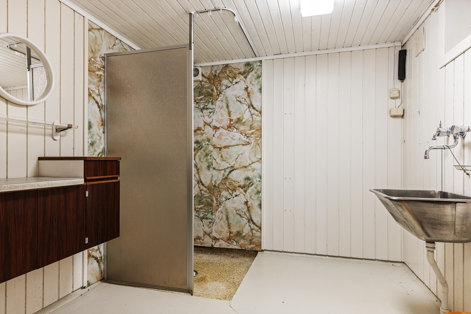 Innredet baderom i kjelleren med malt gulv og våtromsplater på deler av veggene. Øvrige deler av vegger har malt panel. Rommet er innredet med utslagsvask, en eldre innredning og dusjnisje. Rommet må oppgraderes i sin helhet for å imøtekomme dagens krav. Galleribilde