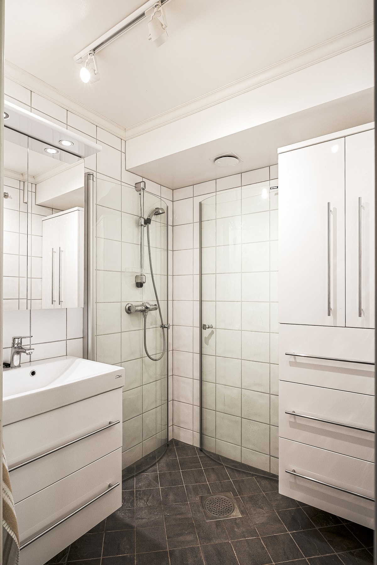 Badet består av dusj, servant med oppbevaring og speil. Galleribilde
