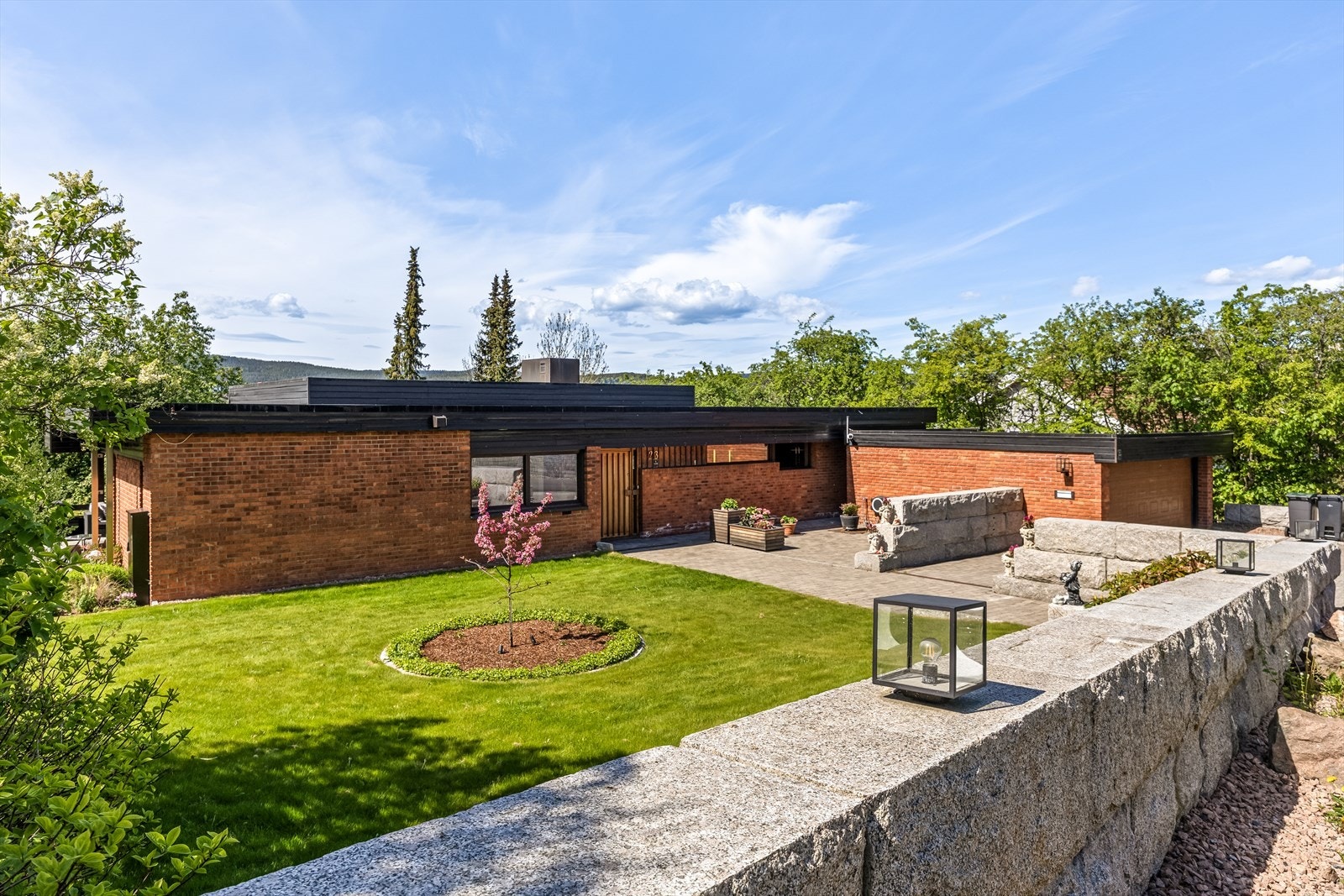 Innbydende og velholdt inngangsparti med steinlagte flater og grøntarealer. Galleribilde