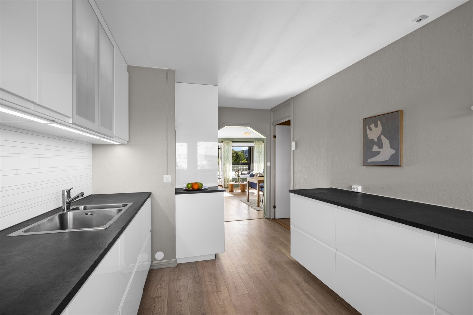 Kjøkkeninnredning med under-/overskap og slette fronter. Benkeplater av laminat med nedfelt kum i rustfritt stål og ett-greps blandebatteri. Galleribilde
