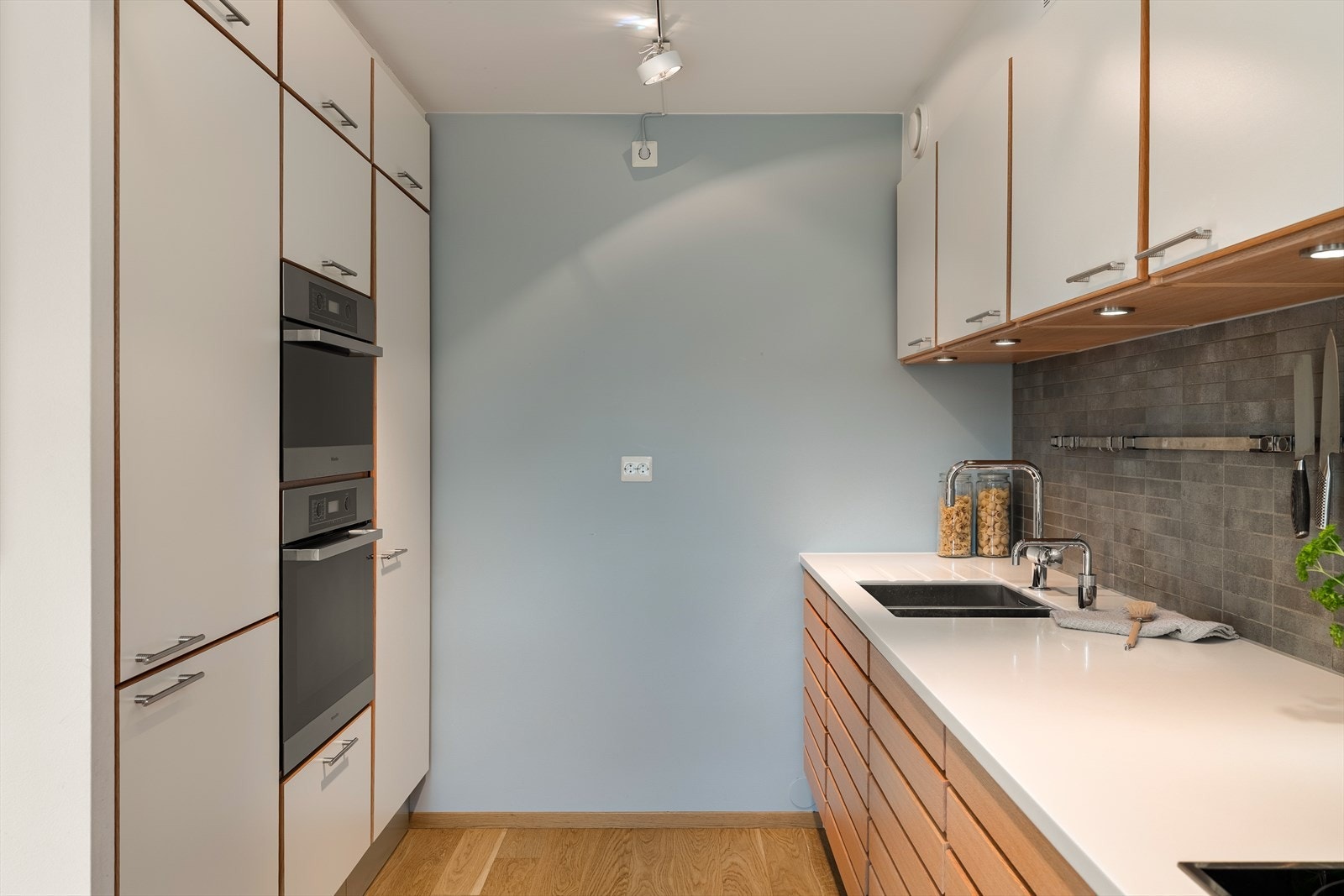 Kjøkkeninnredning fra Multiform med slette fronter på overskap og spilefronter i eik på underskap. Corian benkeplate med dobbel oppvaskkum og Quooker med kokende vann direkte fra springen Galleribilde