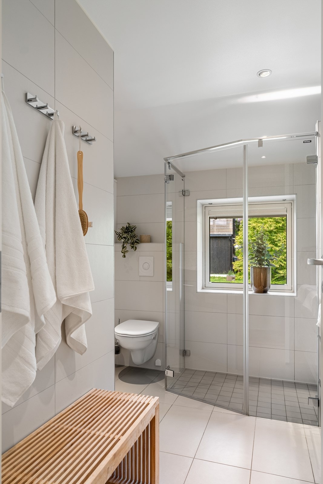 Badet er innredet med vegghengt toalett, høyskap, veggskap og stor baderomsinnredning med dobbel servant og speilskap. Romslig dusj med glassvegger Galleribilde