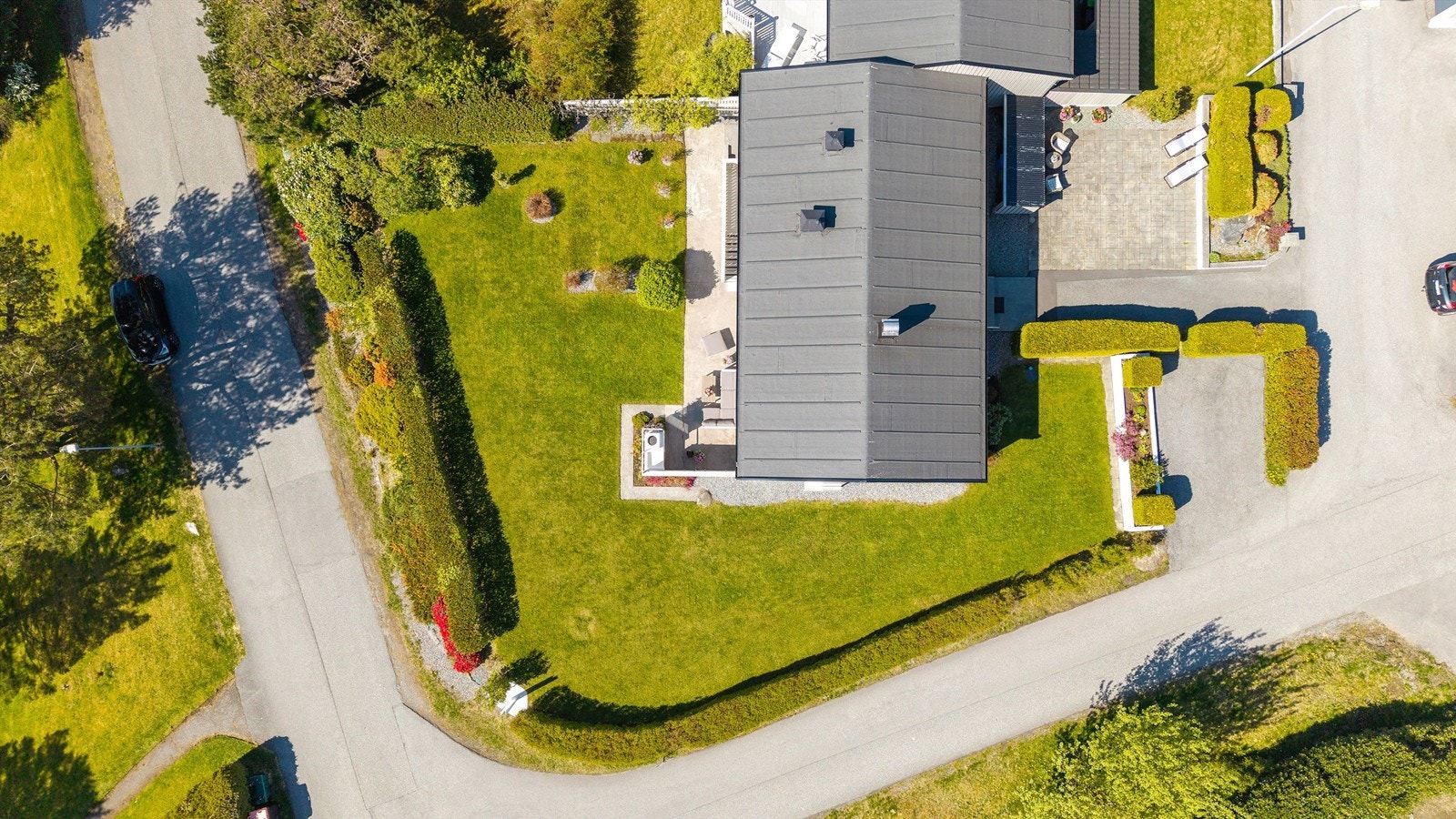 Tomten er opparbeidet med plen, hekk, asfalt og støpte platter Galleribilde