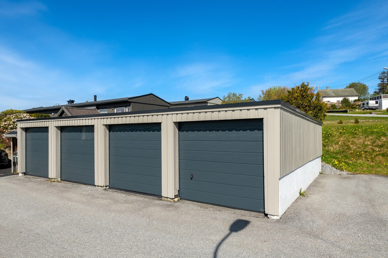 Garasjeplass i felles anlegg med ny leddport i metall og nylig installert ladepunkt for elbil Galleribilde