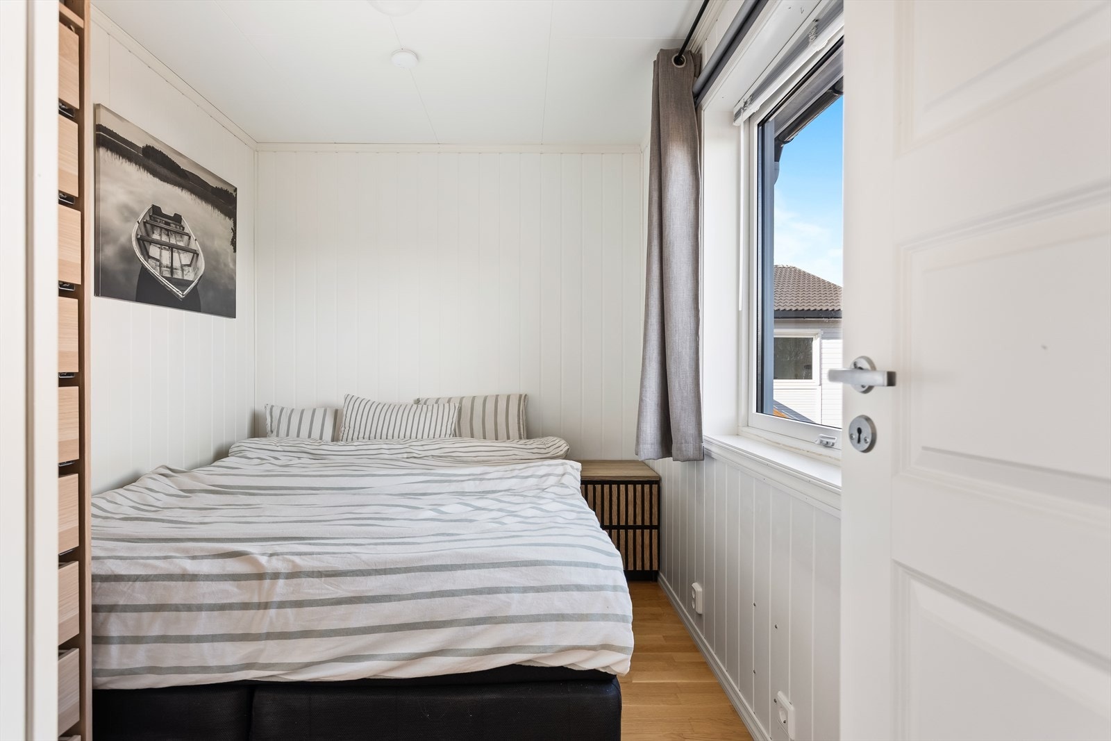 To innbydende og luftige soverom. Hovedsoverommet har hvitmalte, panelte overflater og en vindusflate som sørger for fint lysinnslipp. Galleribilde