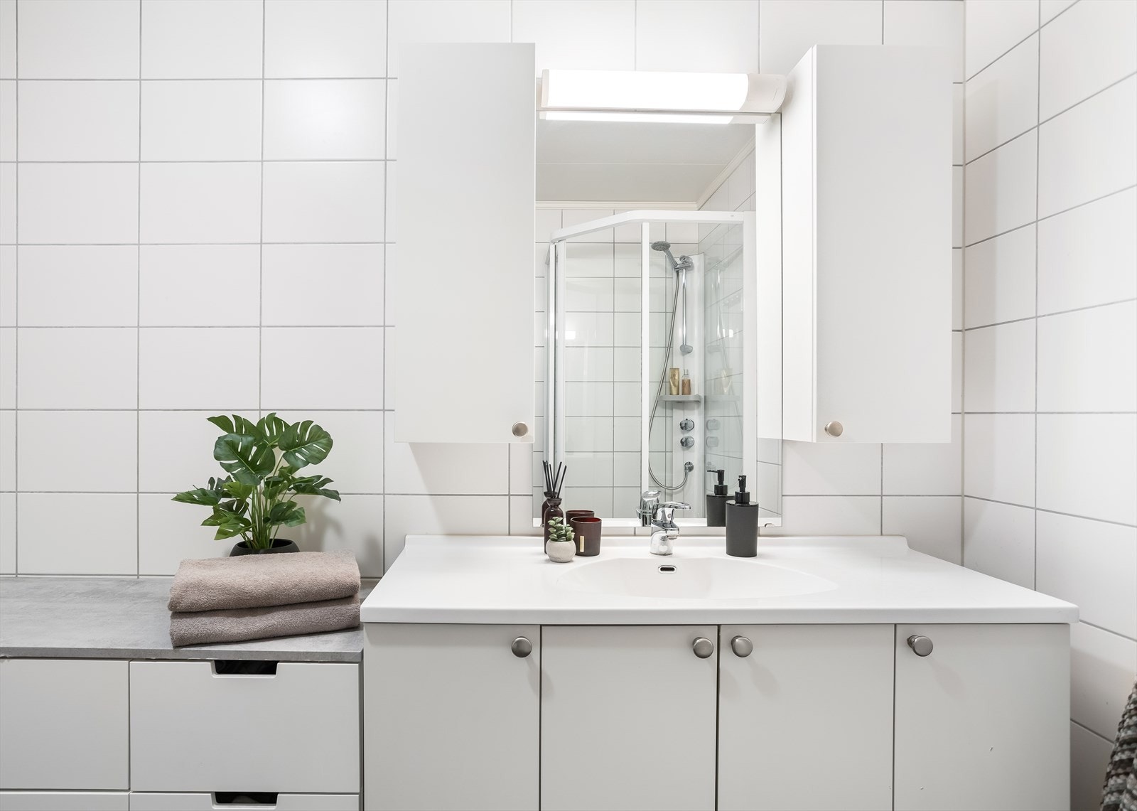 Badet er utstyrt med toalett, servant med skap og dusjkabinett. Galleribilde