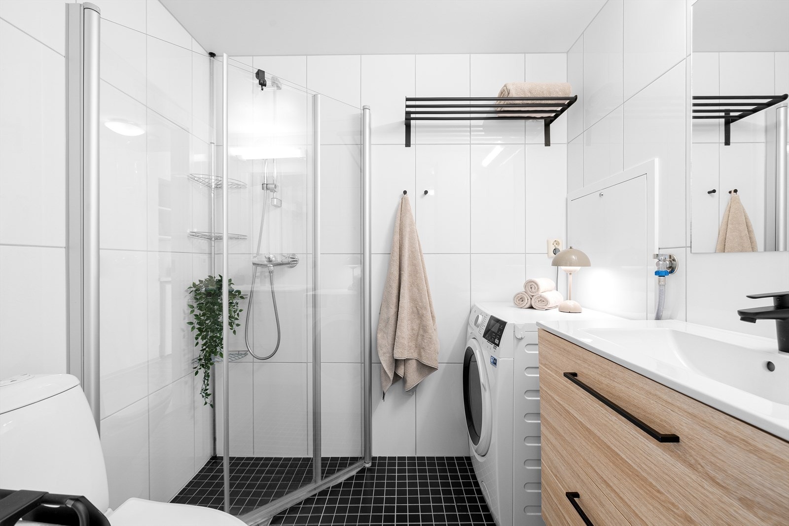 Badet er funksjonelt utstyrt med dusjhjørne med innfellbare dører, servant i skap, gulvmontert toalett og opplegg for vaskemaskin. I tillegg finnes mekanisk avtrekk, rørfordelerskap, stoppeventiler og vannmålere. Galleribilde