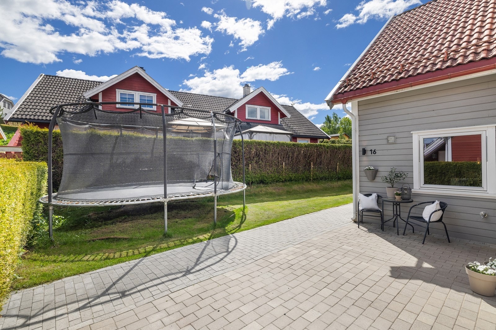 Eiendommen er pent opparbeidet med plen, hekk og steinsatt gårdsplass med biloppstillingsplasser. Galleribilde