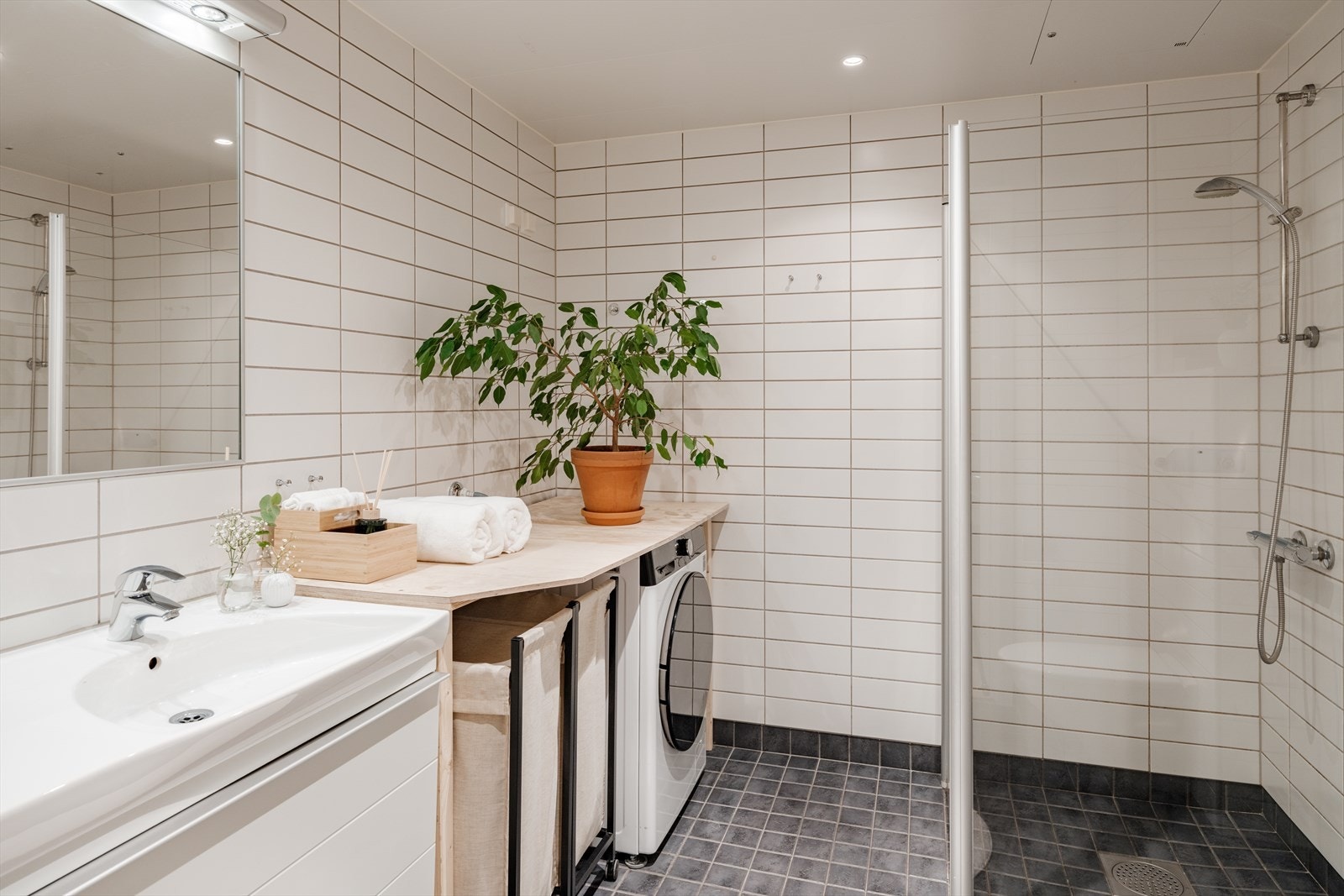 Her får man downlights i himling og varme i gulv. Badet er av god størrelse og er innredet med stor servant over innredning med skuffer, speil med integrert belysning på vegg, vegghengt wc, samt dusjhjørne med innsvingbare dører. Galleribilde