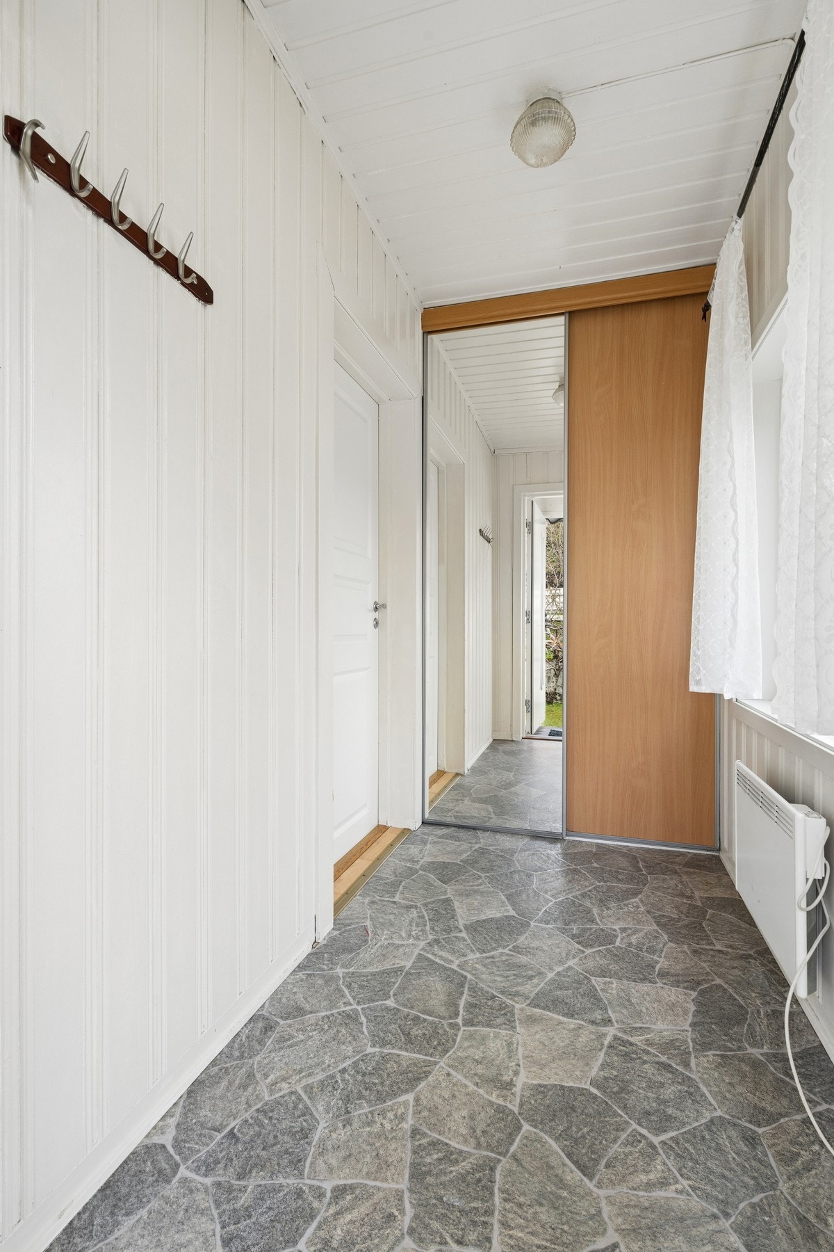 Entré i første etasje med malte panelplater på veggene og plass til yttertøy. Galleribilde
