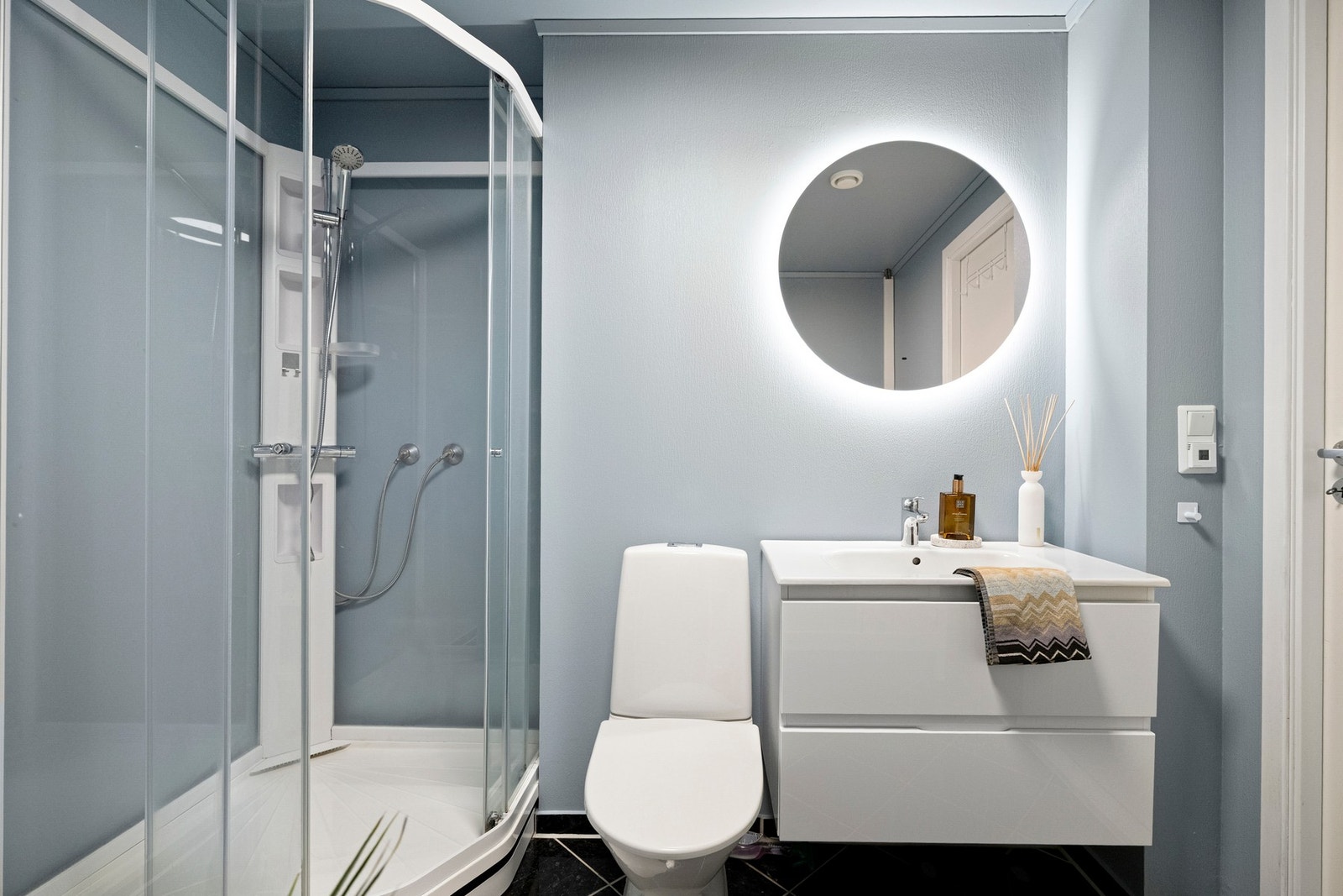 Badet er innredet med gulvvarme, dusjkabinett, vegghengt servantinnredning med heldekkende servant og speil med belysning. Galleribilde