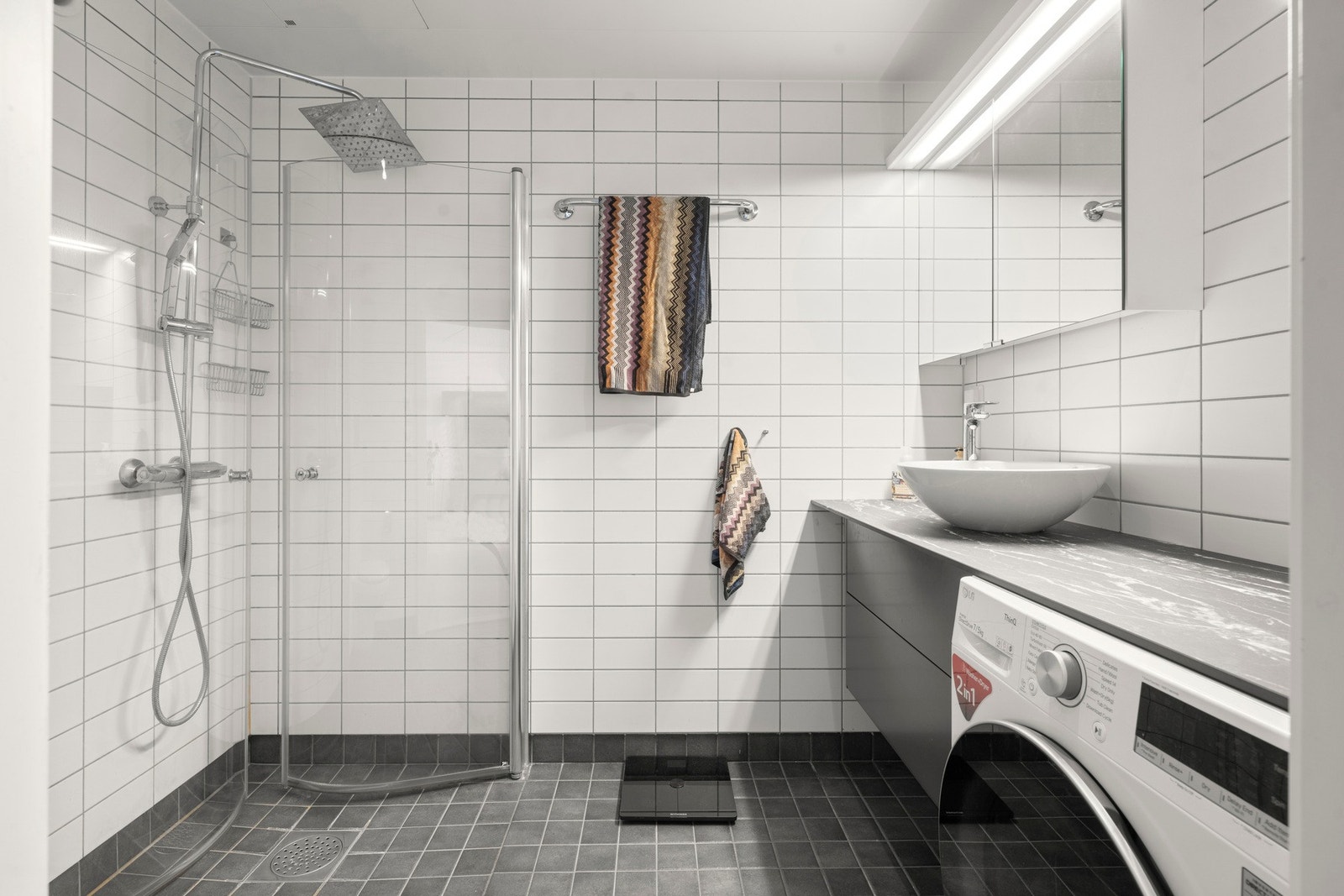 Badet er utstyrt med servant, klosett, dusj på gulv og opplegg for vaskemaskin. Galleribilde