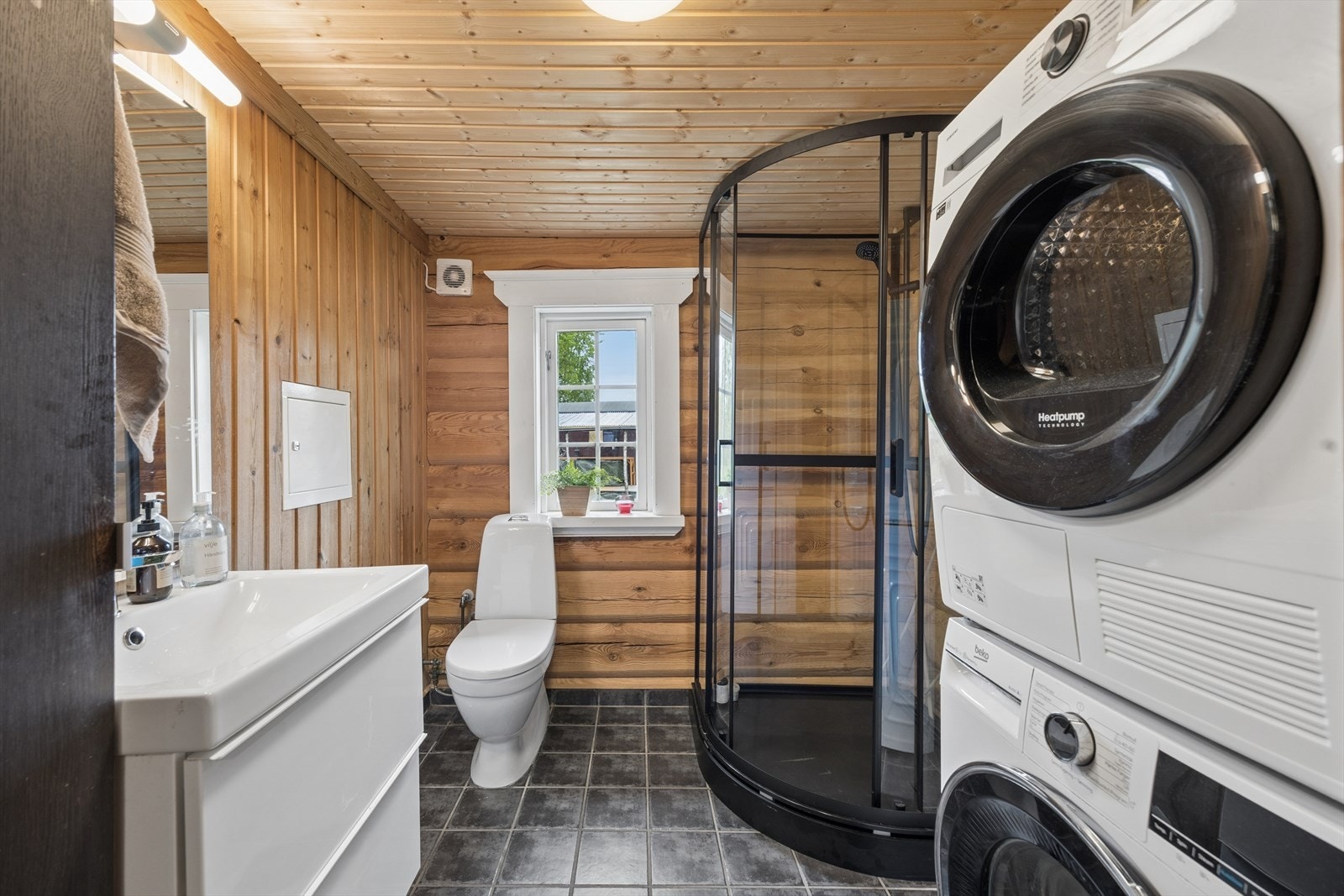 Badet er opprinnelig en bod. Badet er fra 2012 inneholder dusjkabinett, servant med underskap og høyskap, samt opplegg for vaskemaskin. Galleribilde