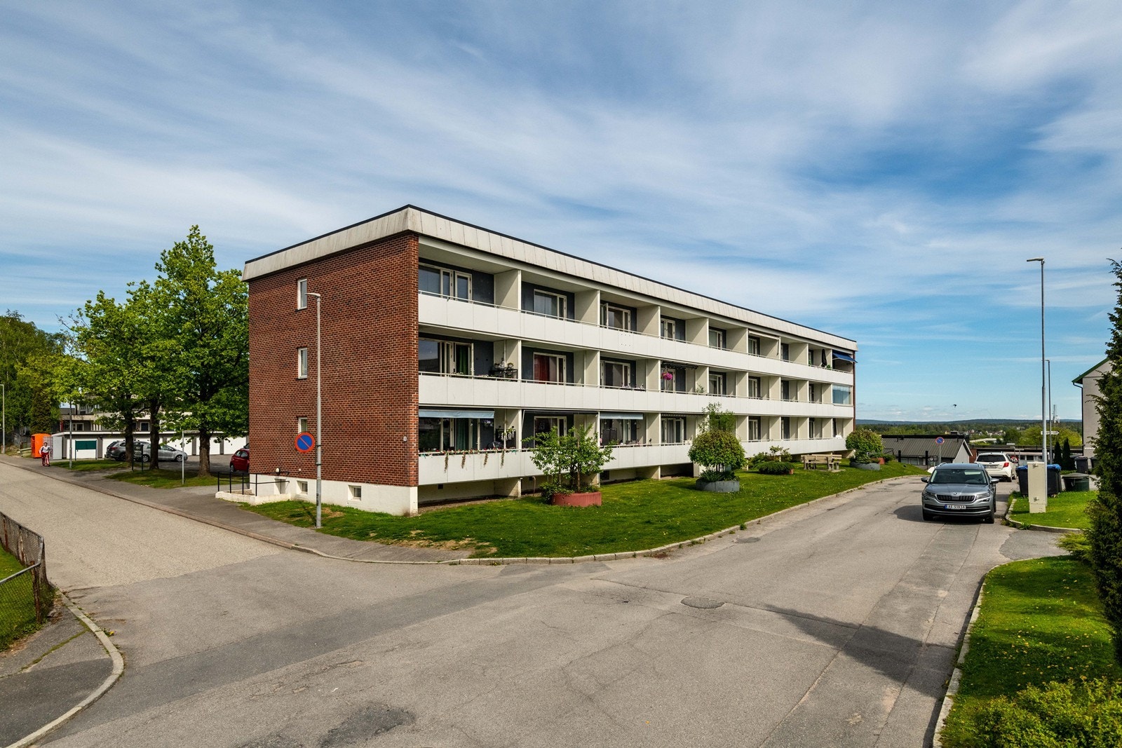 Asfalterte parkeringsplasser og grønne områder omkranser bygningen. Galleribilde