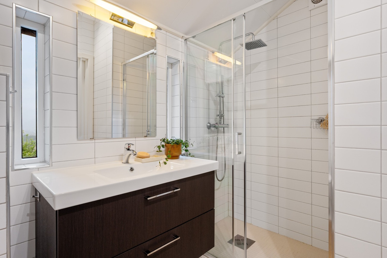 Badet tilknyttet hovedsoverommet har vask med underskap, dusj og vegghengt toalett. Galleribilde