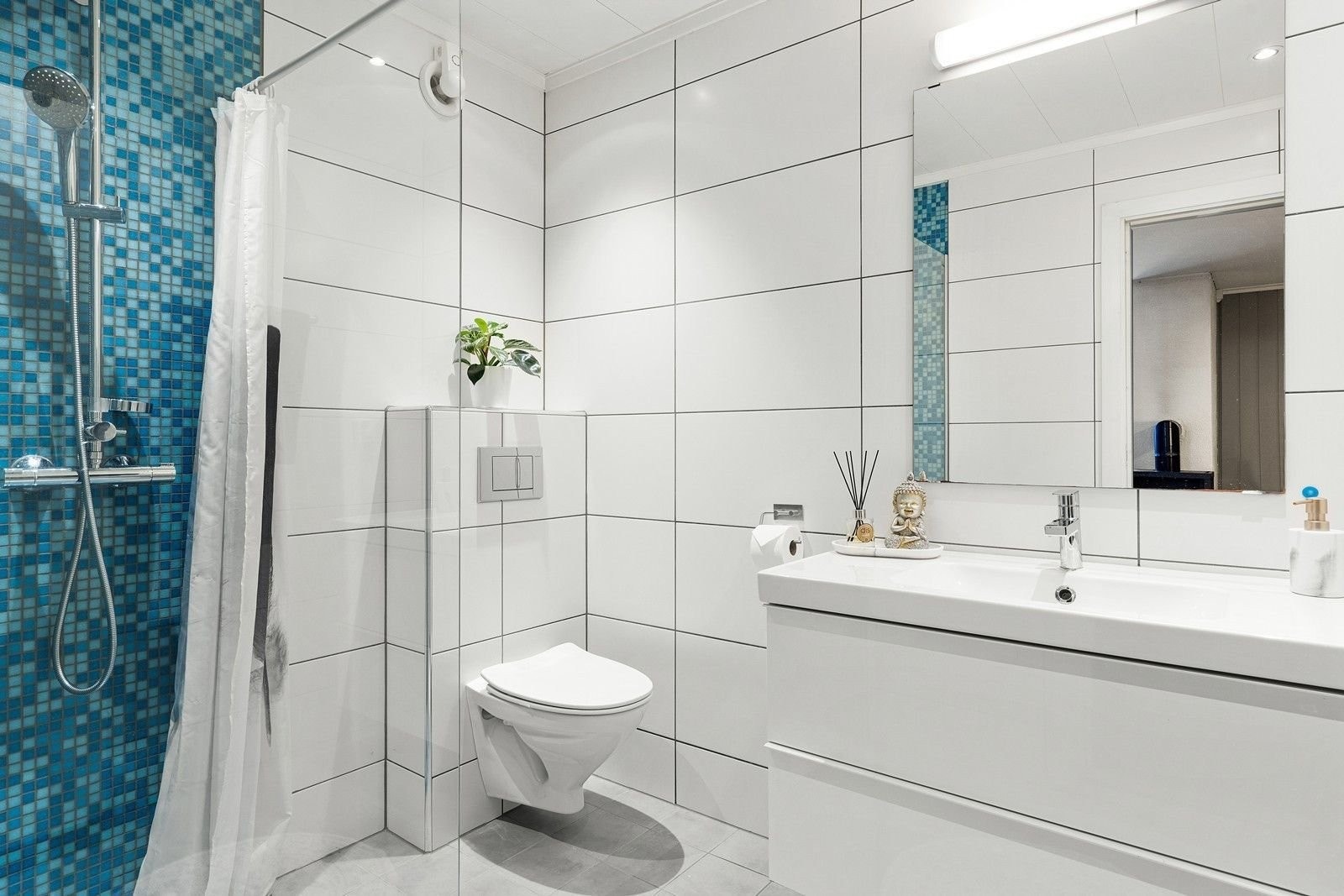 Badet har innredning med nedfelt servant, veggfestet toalett og dusjnisje Galleribilde