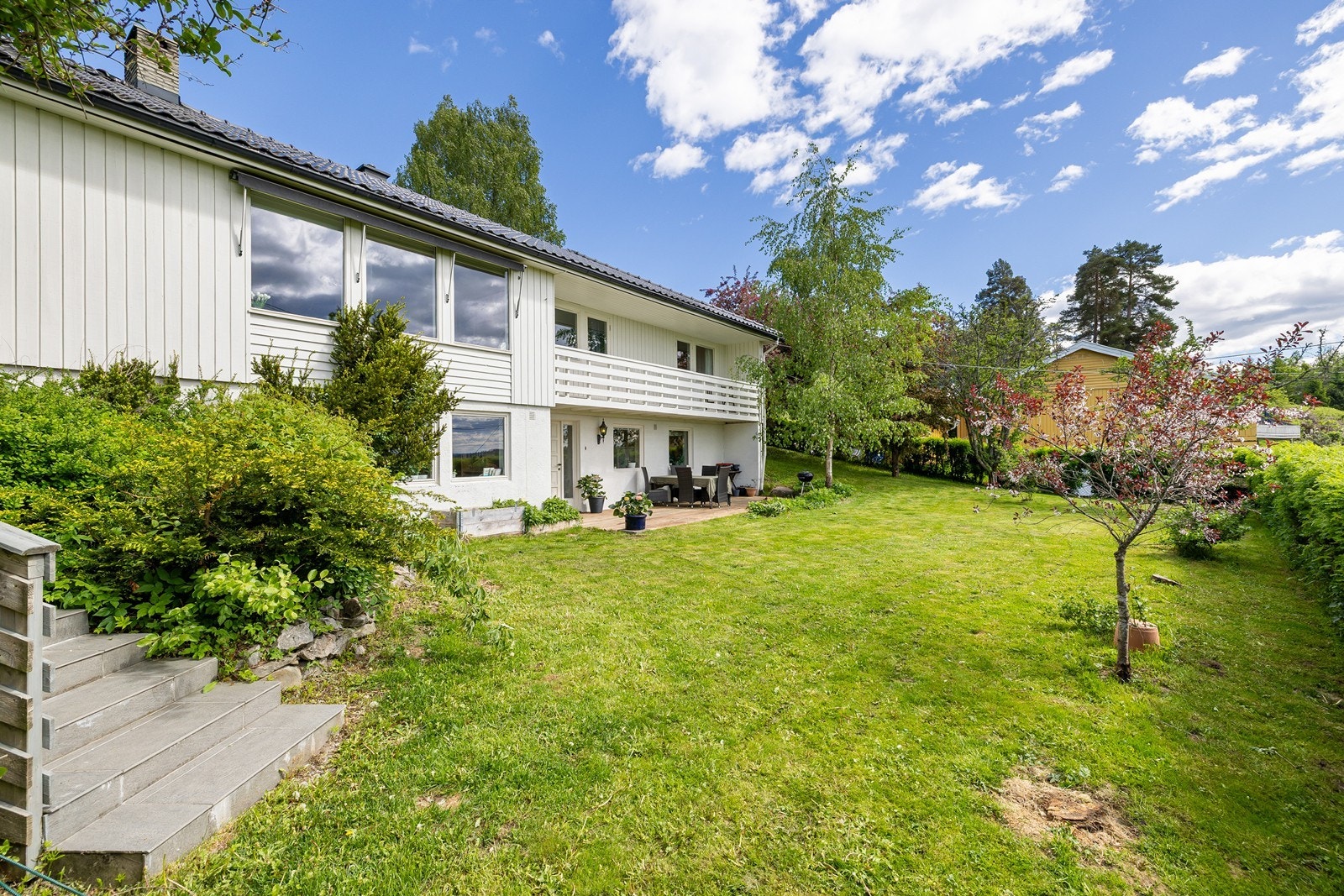Solforholdene er optimale, og uteområdet er en oase med en skjermet, omkranset hage, flere fine uteplasser og en lun utestue med peis Galleribilde