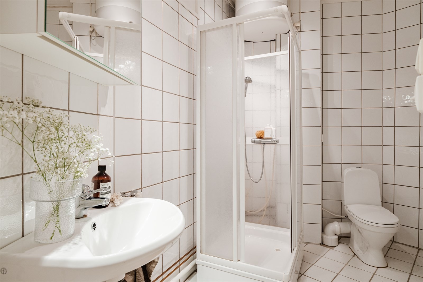 Helfliset bad med frittstående toalett, dusjkabinett og servant med blandebatteri. Badet har opplegg for vaskemaskin. Galleribilde