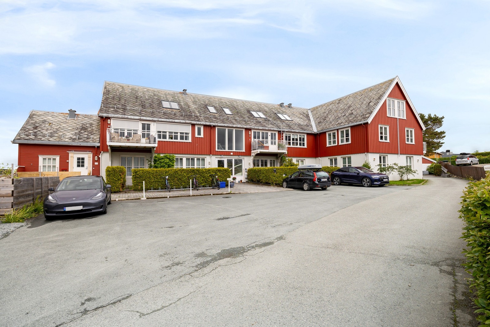 Fasadebilde. Opparbeidet og innbydende tun med parkeringsplasser og grønne omgivelser. På tunet har du sykkelparkering i stativ. På baksiden av eiendommen har du store grøntarealer. Galleribilde