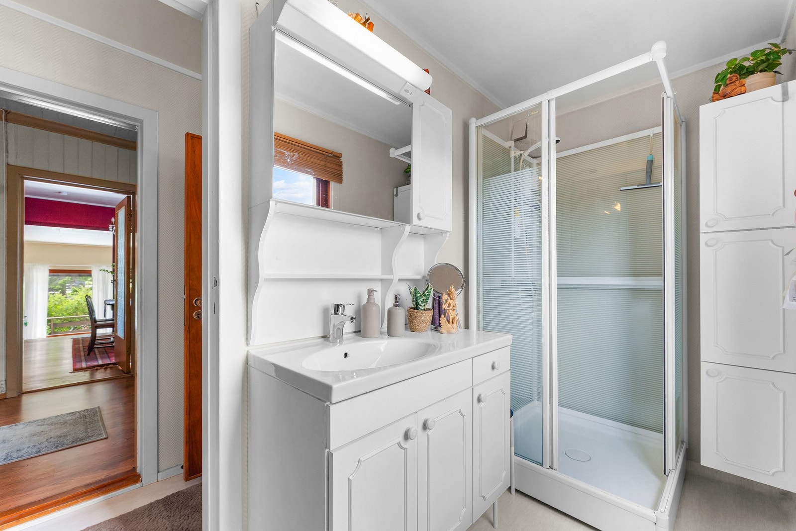 Badet har en praktisk og funksjonell utforming med baderomsinnredning bestående av benkeskap, veggskap og høyskap med profilerte fronter, som gir gode oppbevaringsmuligheter, servant og dusjkabinett. Galleribilde