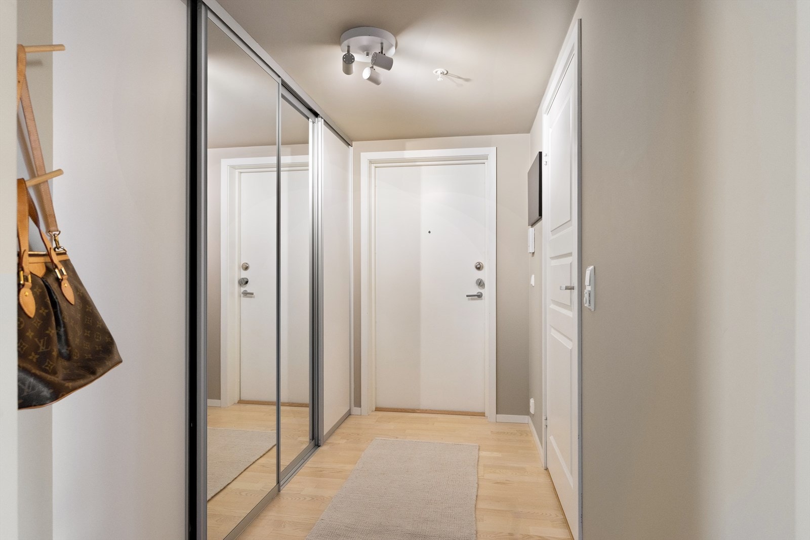 Leiligheten ønsker deg velkommen med en romslig og delikat entré. Her er det god plass til å henge fra seg yttertøy i en praktisk skyvedørsgarderobe med speilfronter. Galleribilde