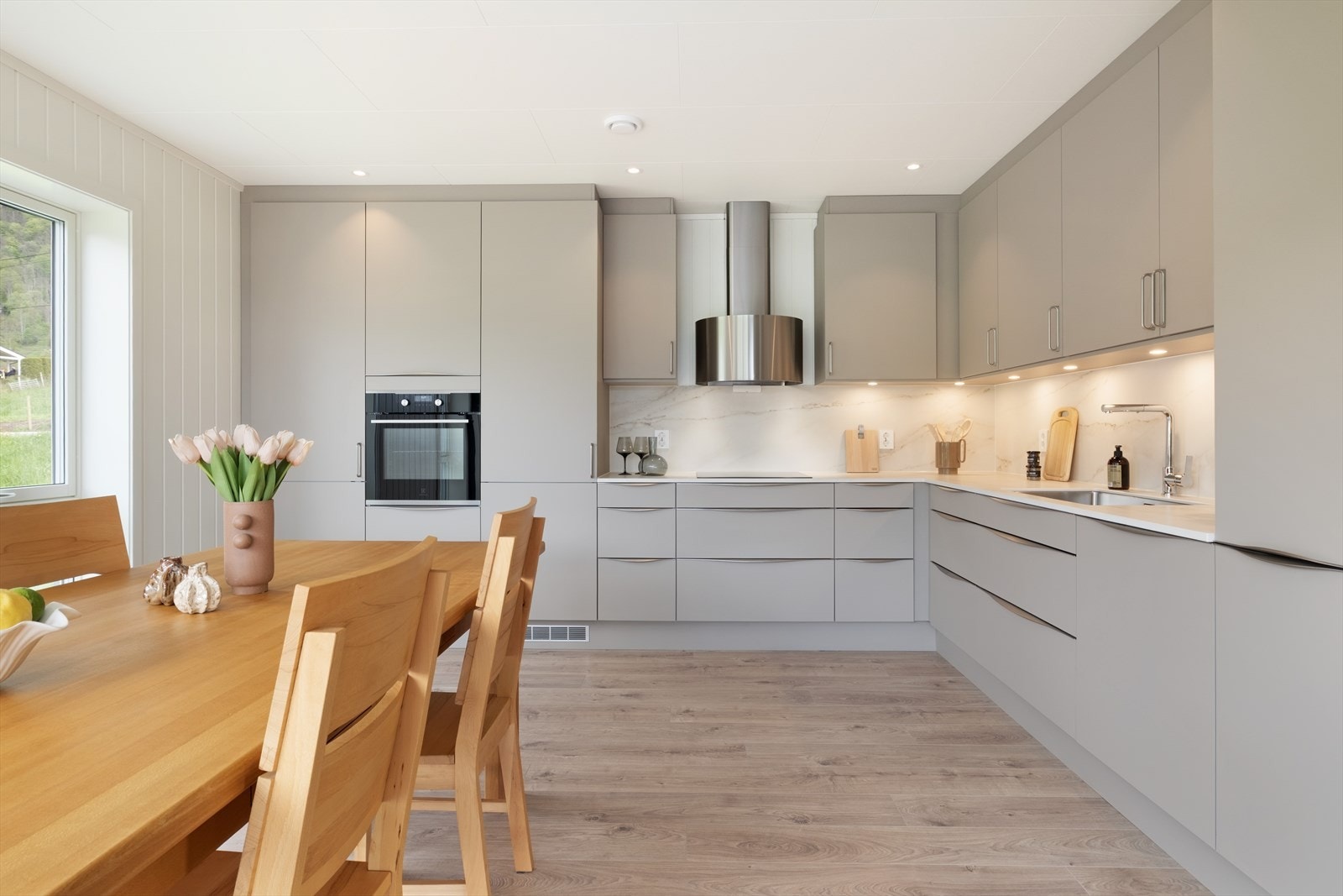 Lekkert og stilreint kvalitetskjøken frå Aubo og har innredning med glatte frontar og benkeplate frå Dekton. Innredningen går langs to veggar i ein L-form med god arbeidsflate og rikelig med skapdørar og skuffer. Galleribilde