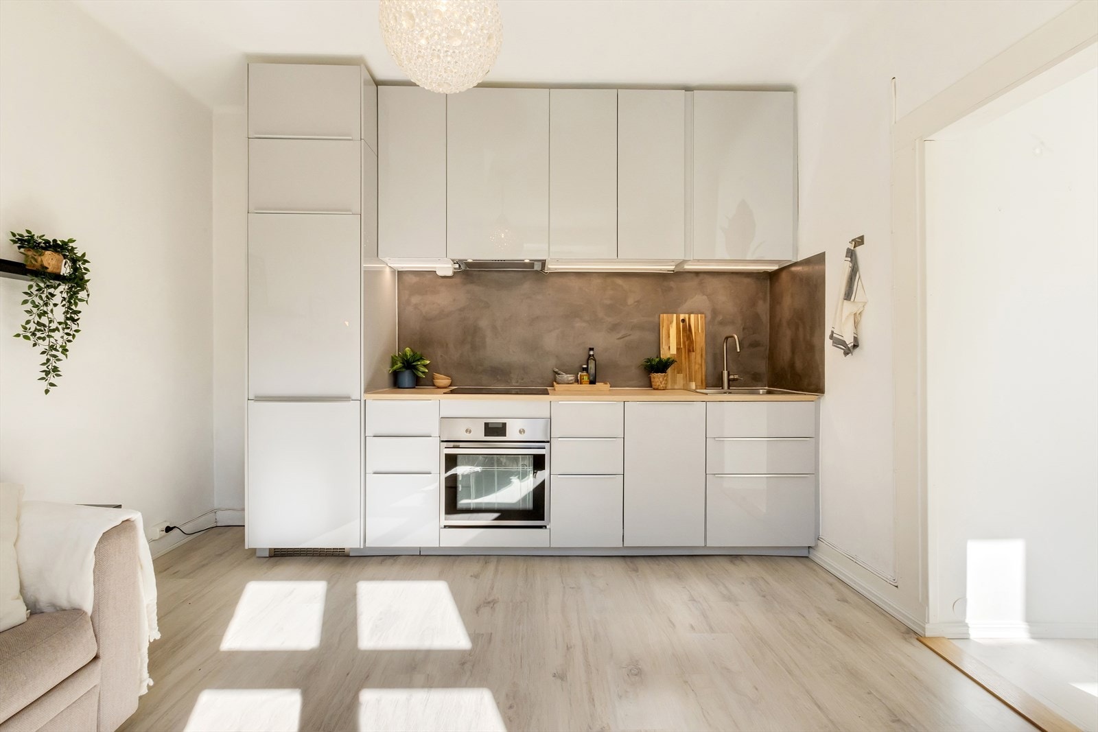 Tidsriktig kjøkken fra Ikea med glatte, grå fronter, mikrosement på veggen over kjøkkenbenken og benkeplate i laminat. Galleribilde